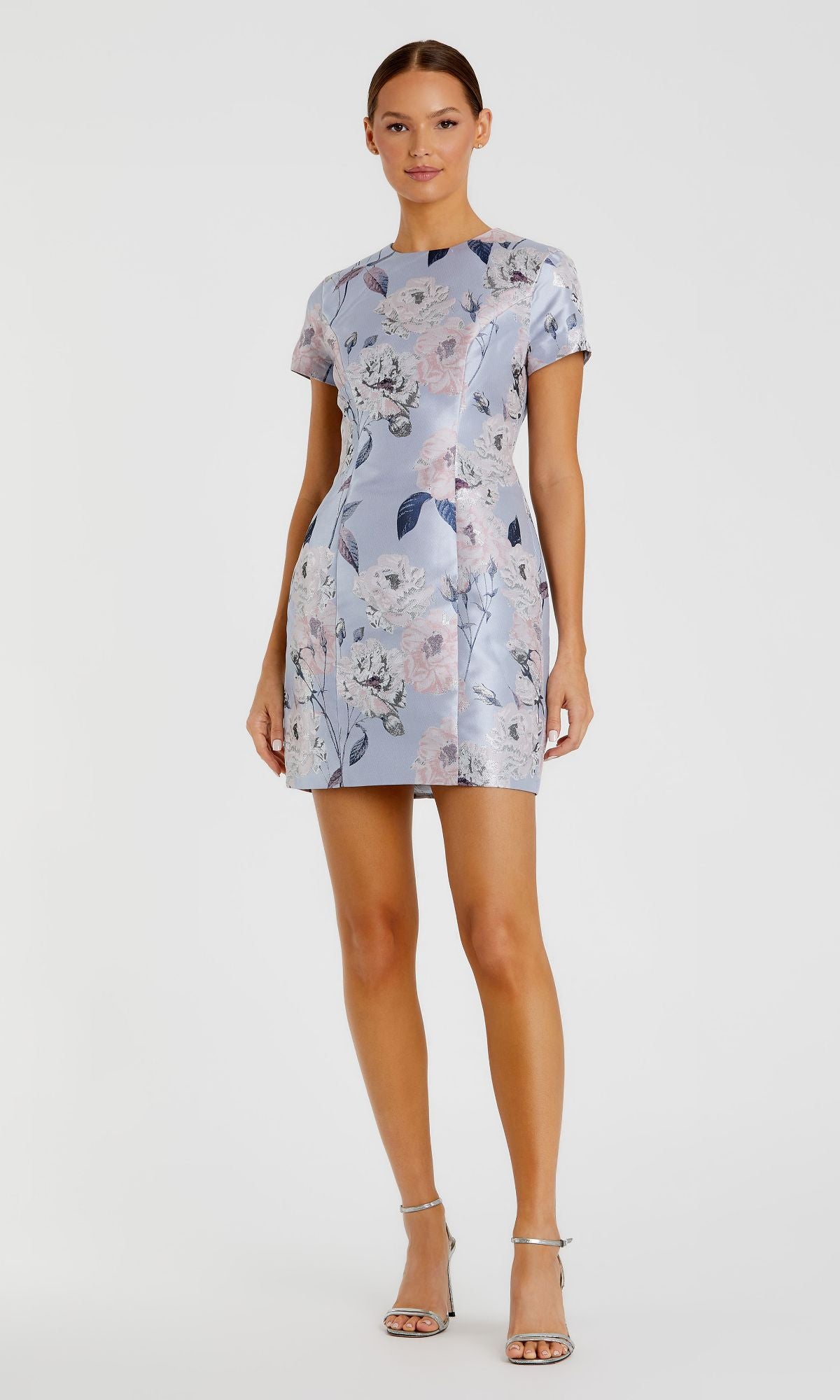 A woman wears the Mac Duggal Floral-Print Wedding-Guest Dress 11614 with short sleeves and silver high-heeled sandals, standing against a plain white background.