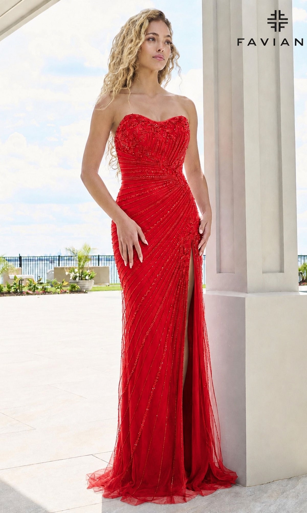 A woman wearing a Faviana 11616 long prom dress in red, featuring a floor-length strapless sweetheart design with beadwork and a high leg slit.