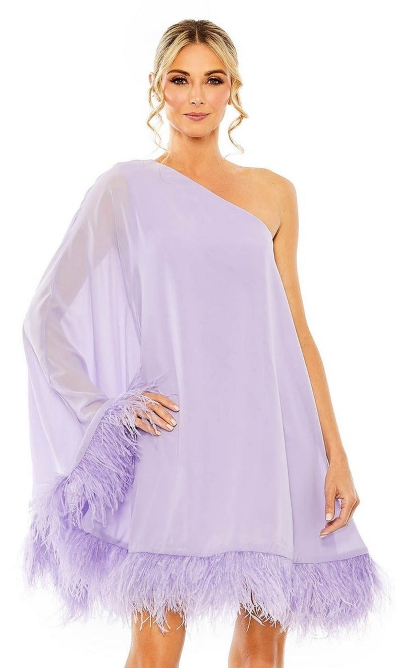 A woman models the Mac Duggal 11623 short wedding guest dress in light purple, showcasing its one-shoulder design, sheer sleeve, and feather-trimmed hem against a white background.
