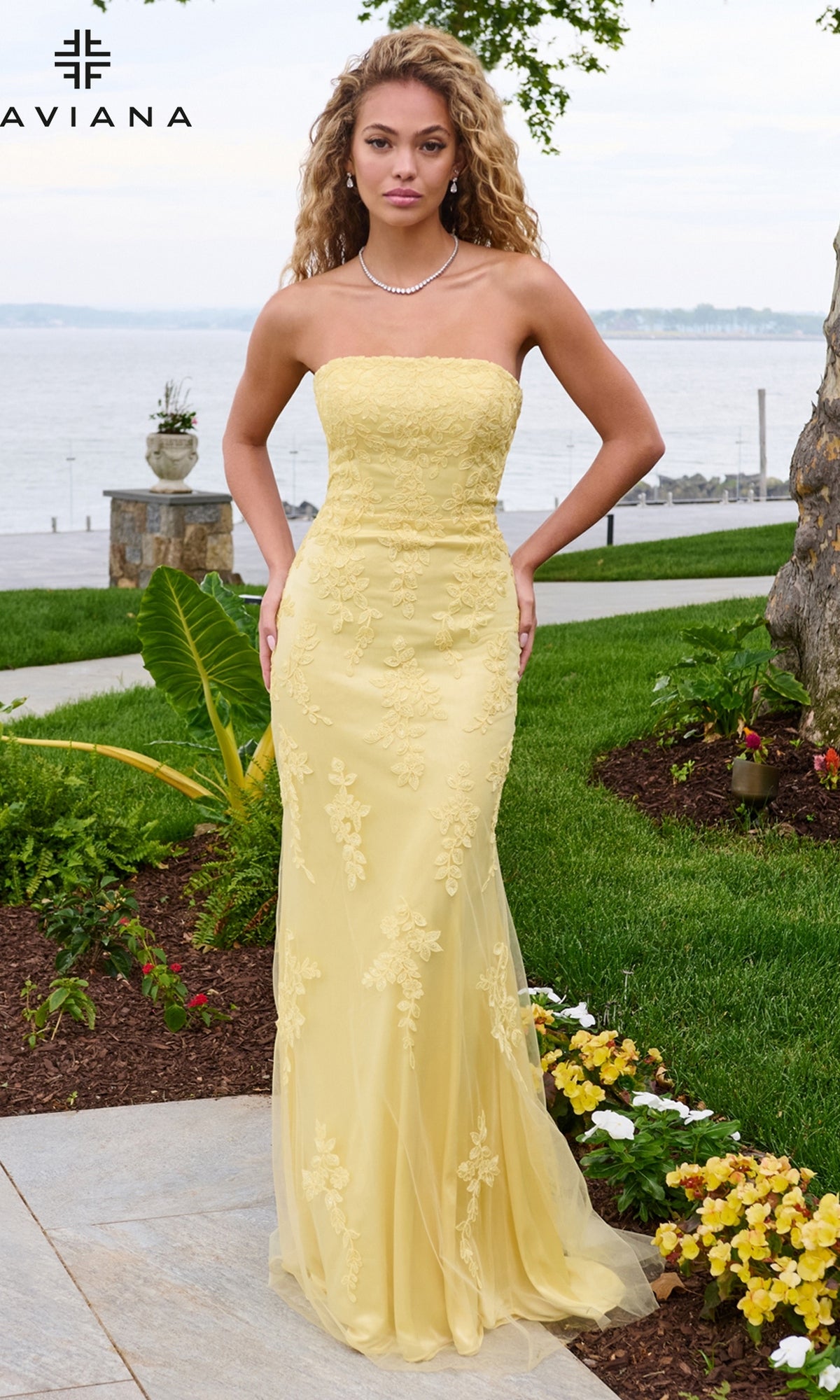 A woman wearing a yellow Long Prom Dress: Faviana 11627, a strapless, floor-length gown with floral lace appliques.