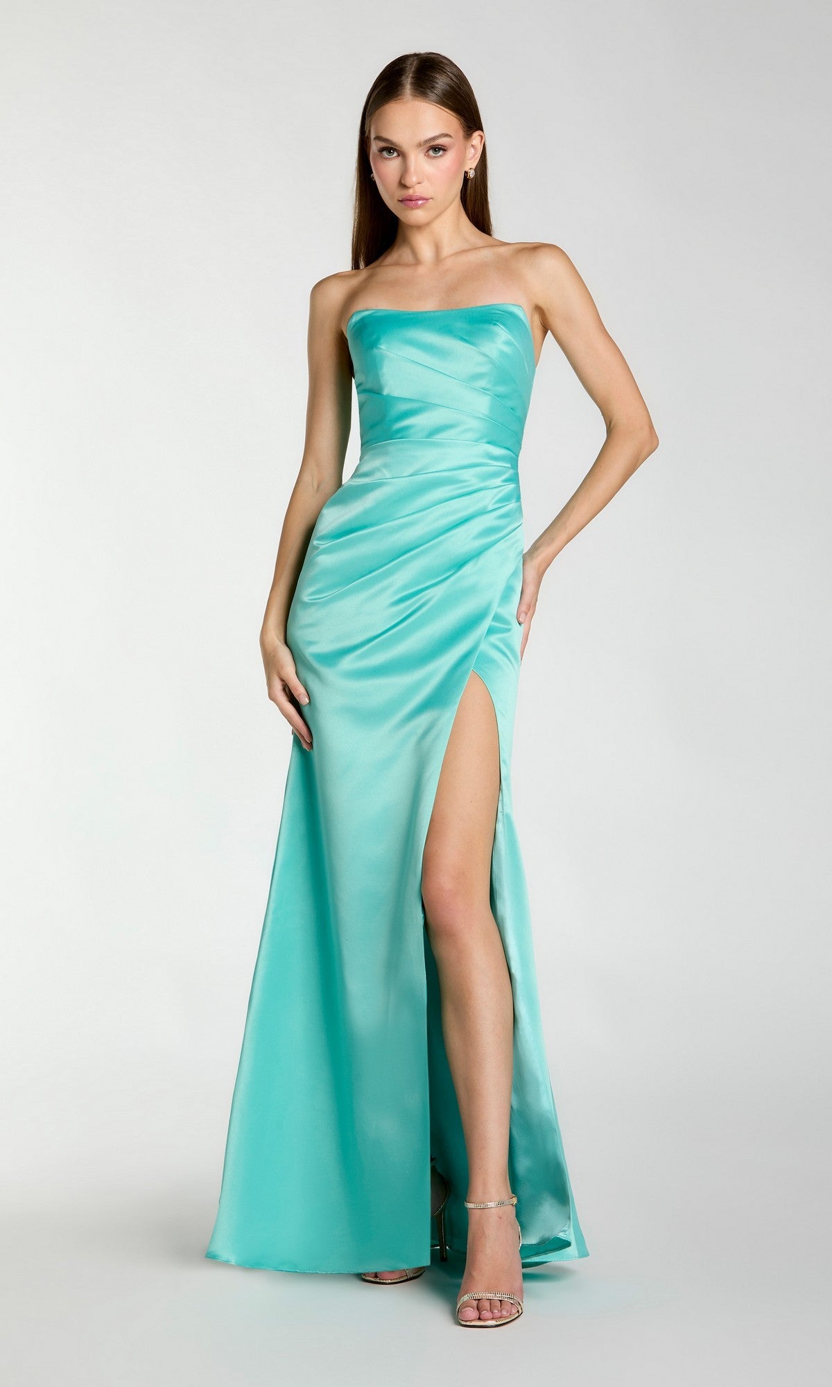 A woman wears the Sherbet Orange Long Prom Dress (Mac Duggal 11653), a strapless satin gown with a thigh-high slit, posing gracefully against a plain light background.
