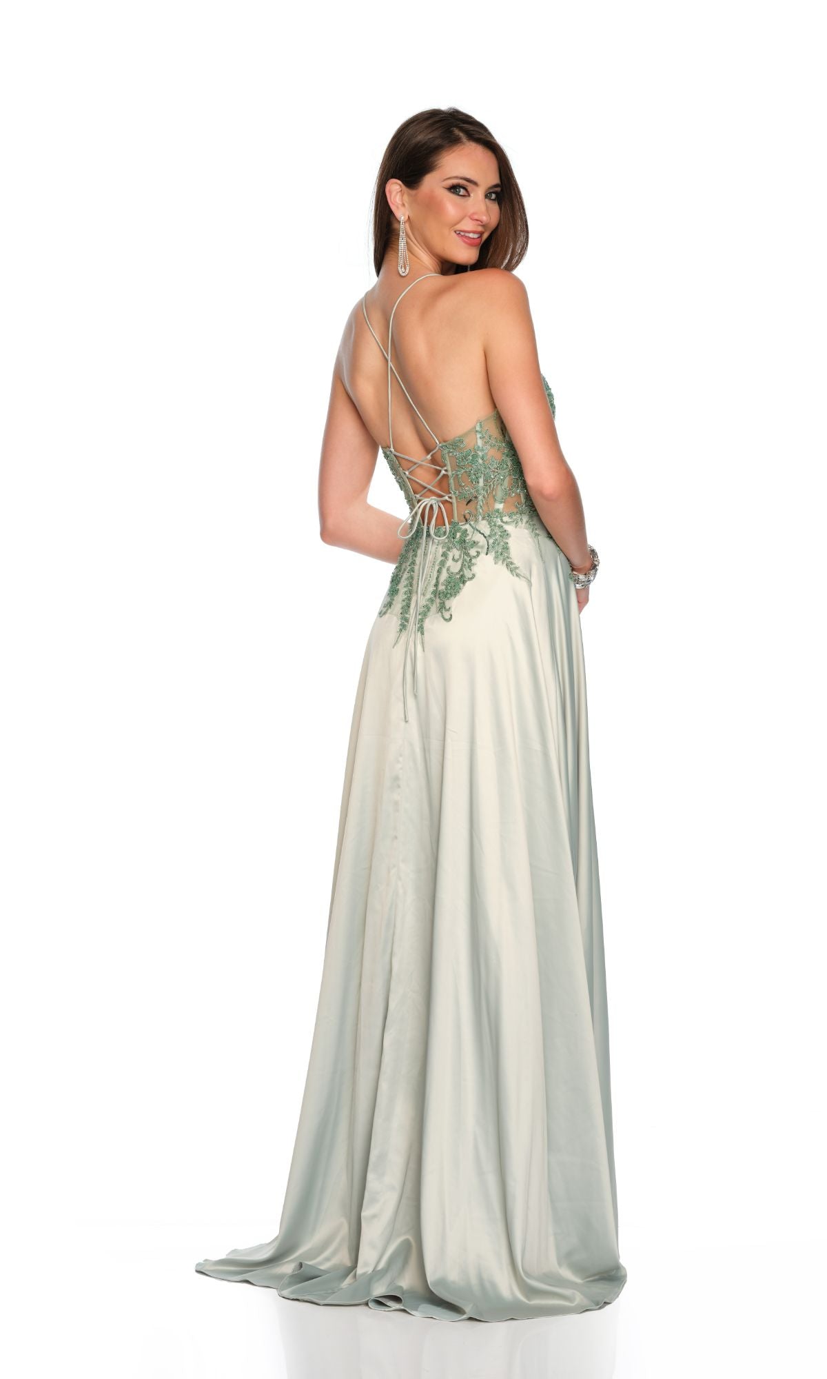 A woman stands against a white background, looking over her shoulder in the Long Formal Dress 11654 by Dave and Johnny—featuring pastel sage green fabric, lace detailing, a sweetheart neckline, and an open back.