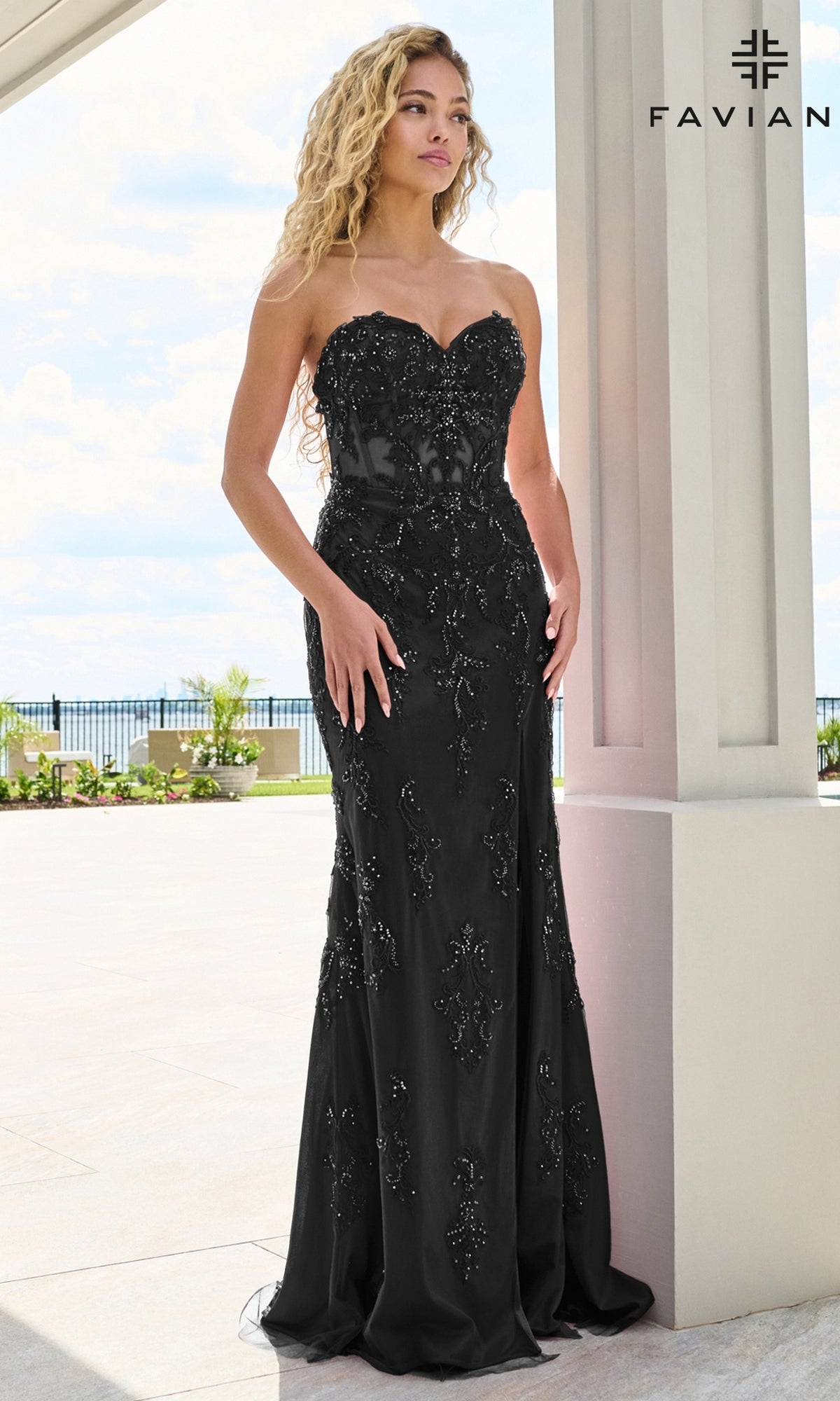A woman wears a black Faviana 11654 floor-length prom dress featuring a strapless sweetheart neckline, intricate beaded lace appliques, and a lace-up back.