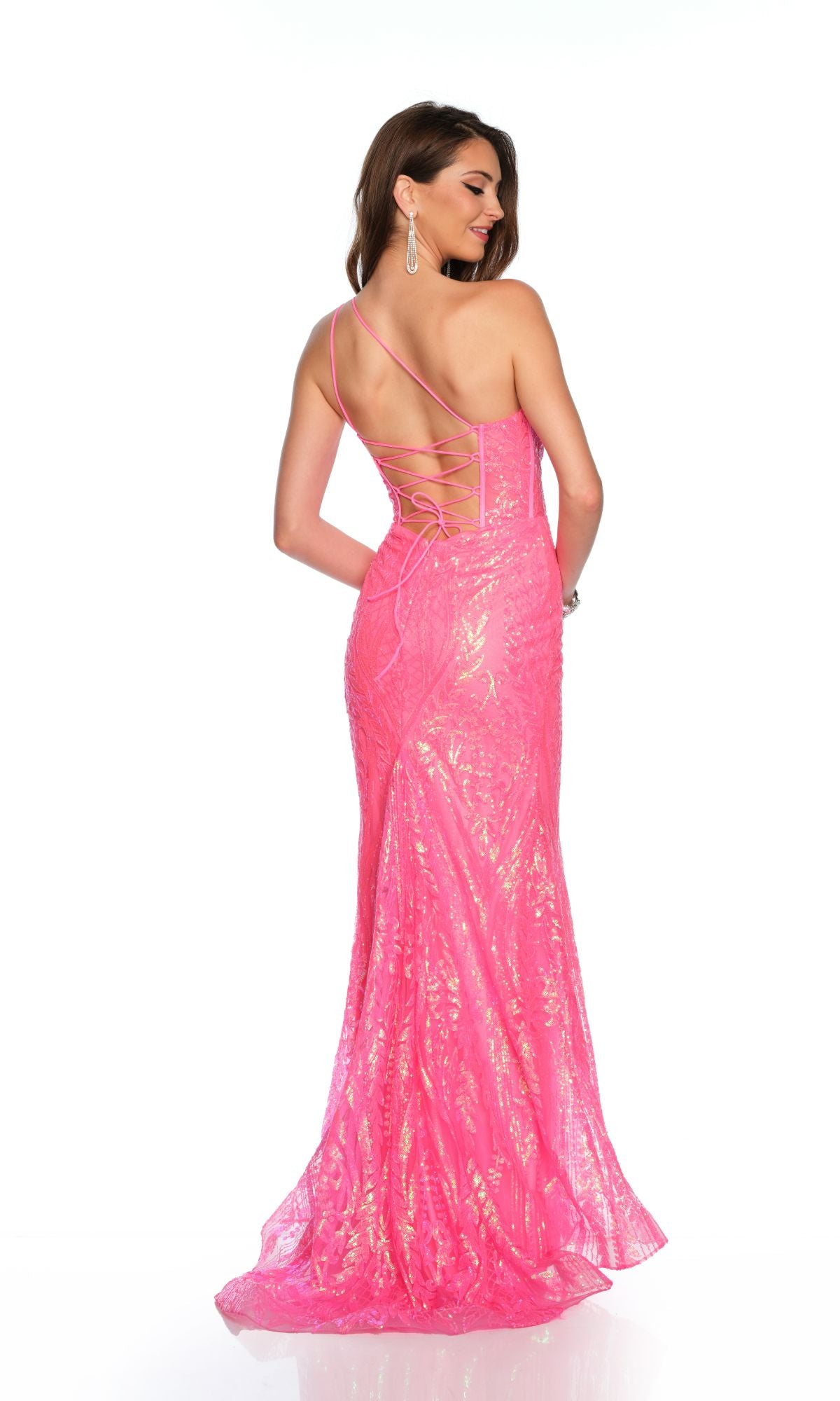 A woman models the Dave & Johnny Long Prom Dress 11668 in hot pink, featuring floor-length and backless lace-up details, as she stands turned slightly away from the camera.