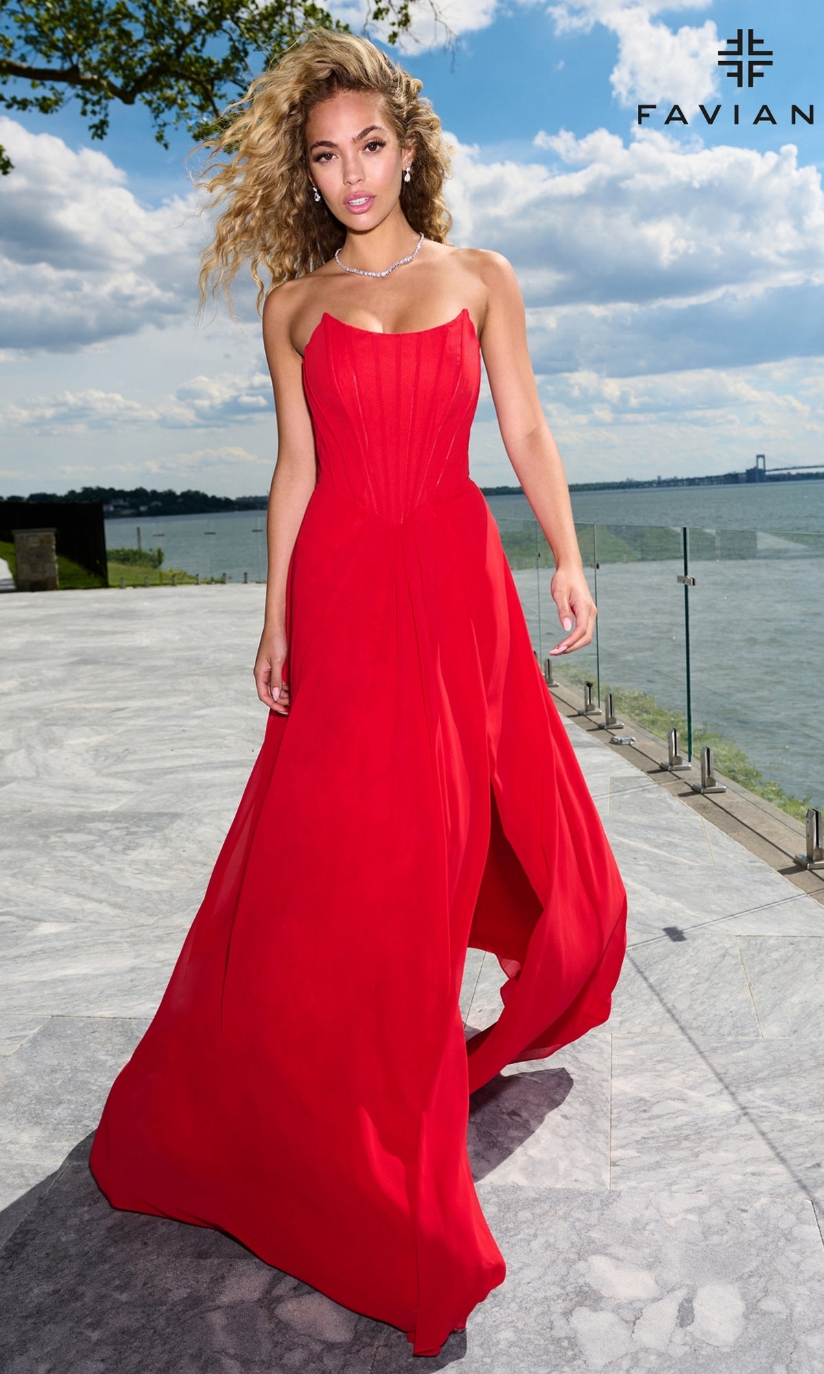A woman wearing a Faviana 11672 floor-length red strapless corset prom dress with a bodice and a high slit.