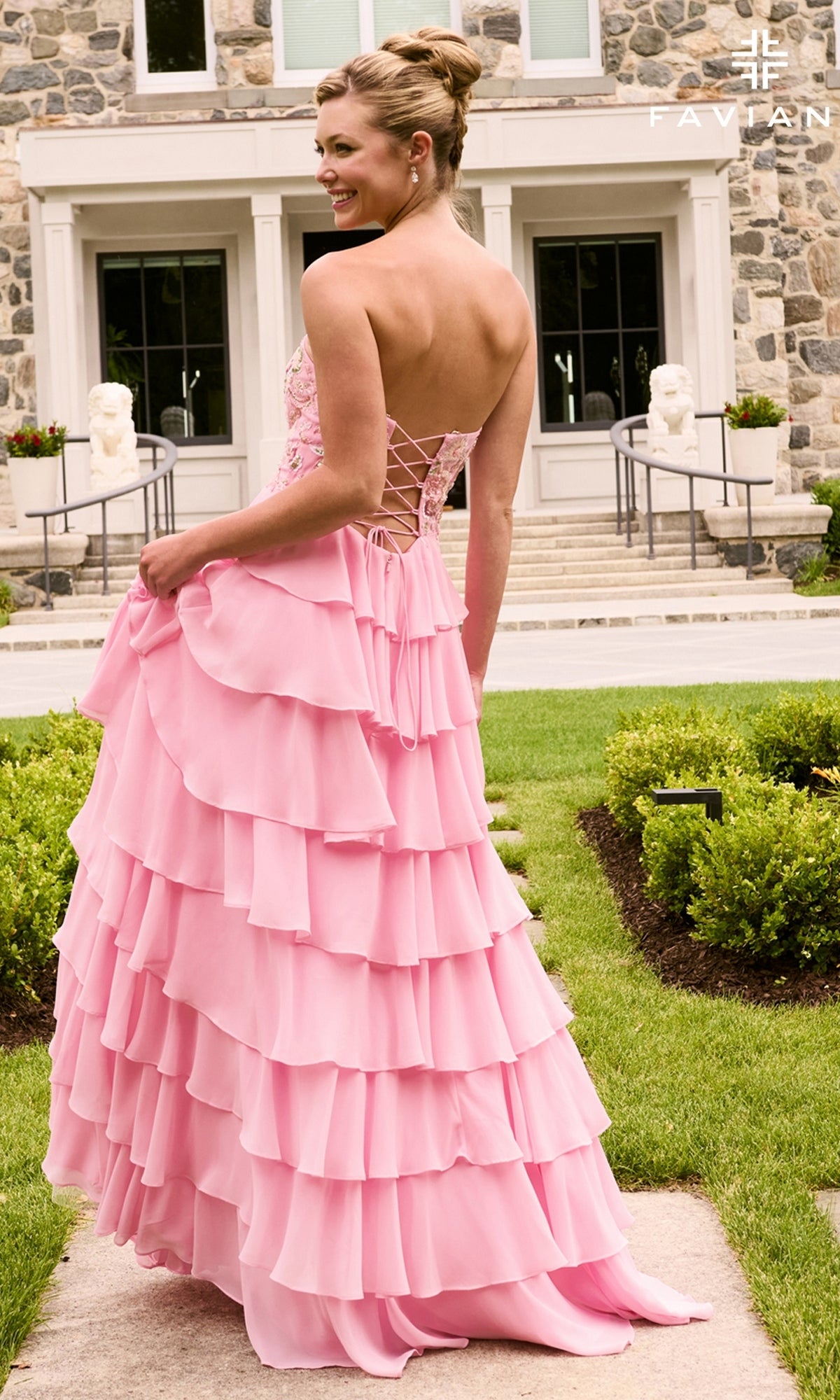 A woman wearing a pink, strapless Long Prom Dress: Faviana 11675 featuring tiered ruffles and a lace-up back.