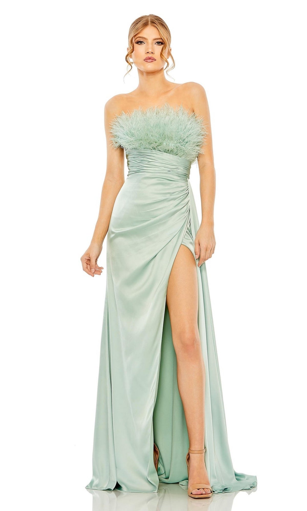 A woman wears the Mac Duggal Long Formal Dress 11690, a seafoam green satin strapless gown with a feather bodice, ruched waist, high slit, and strappy heels.