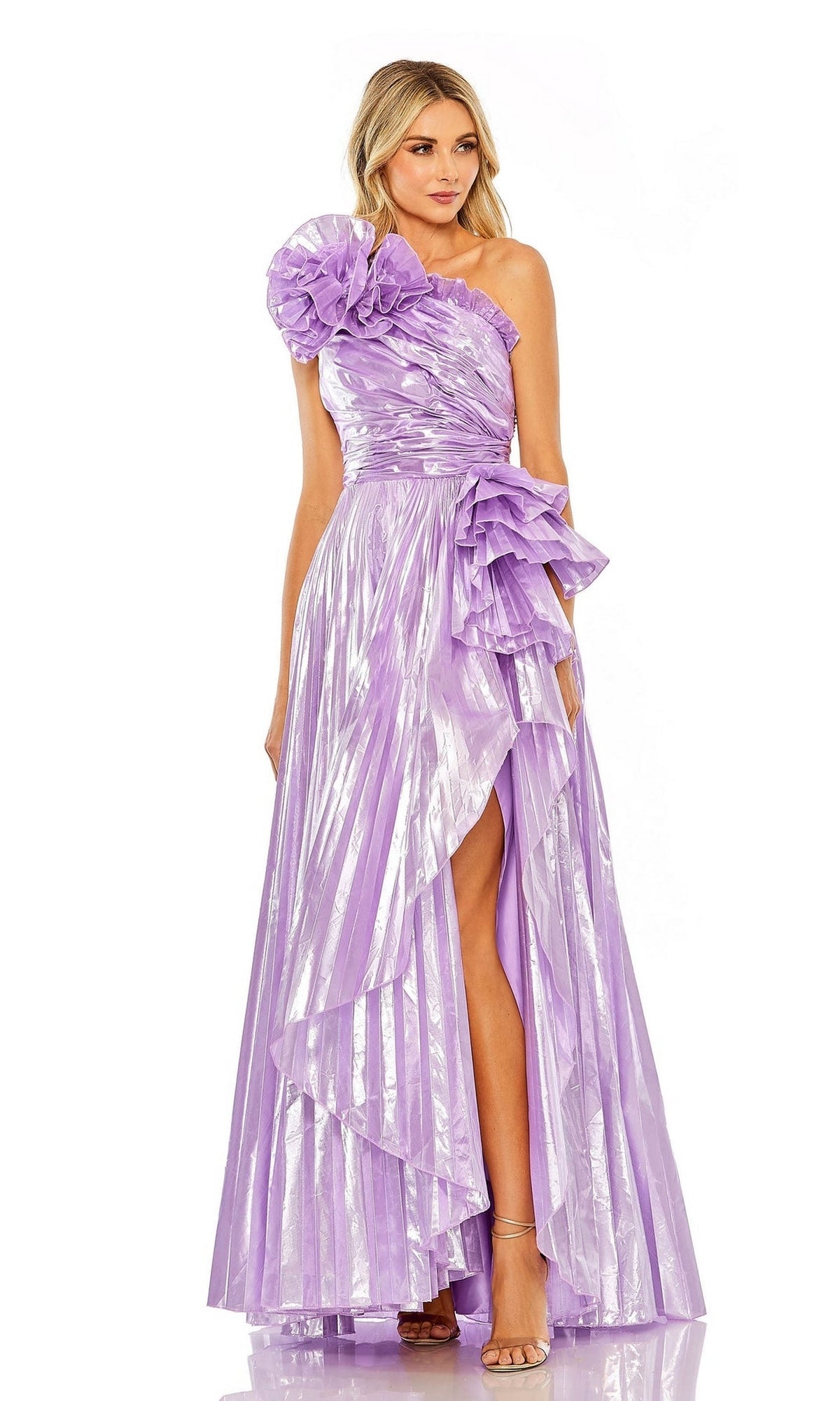 A woman models the Long Formal Dress 11696 by Mac Duggal, featuring a shiny one-shoulder design with a large floral accent and high slit, standing against a white background.