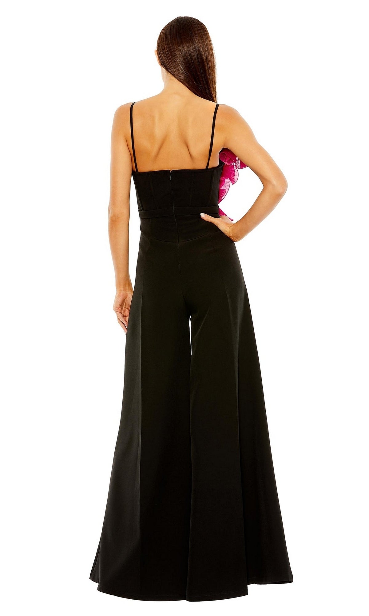 A woman faces away, wearing the Mac Duggal Long Formal Jumpsuit 11767—black, with wide legs and thin shoulder straps—while holding a pink flower accessory.