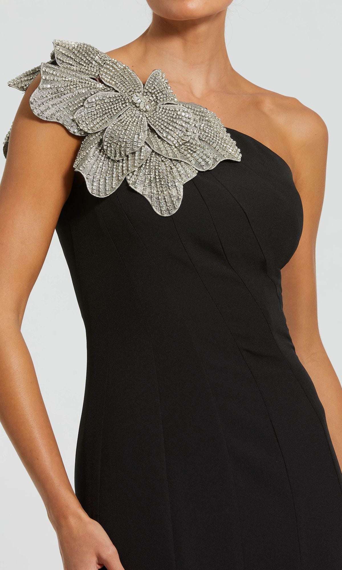 A woman wears the Beaded-One-Shoulder Prom Gown: Mac Duggal 11810, featuring a decorative silver beaded floral applique on the shoulder.