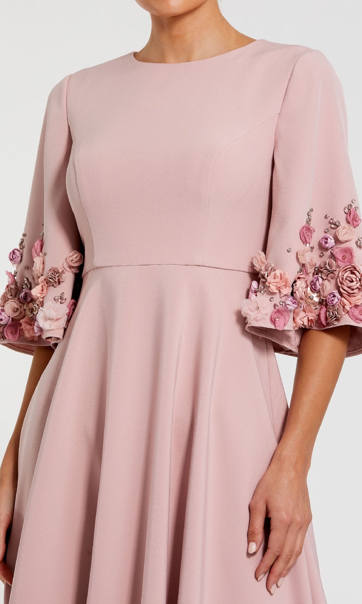 A woman wears the Mac Duggal 11854 Bell-Sleeve Long Formal Dress in light pink, styled with elbow-length flared sleeves embellished with pink floral appliqués and bead details.