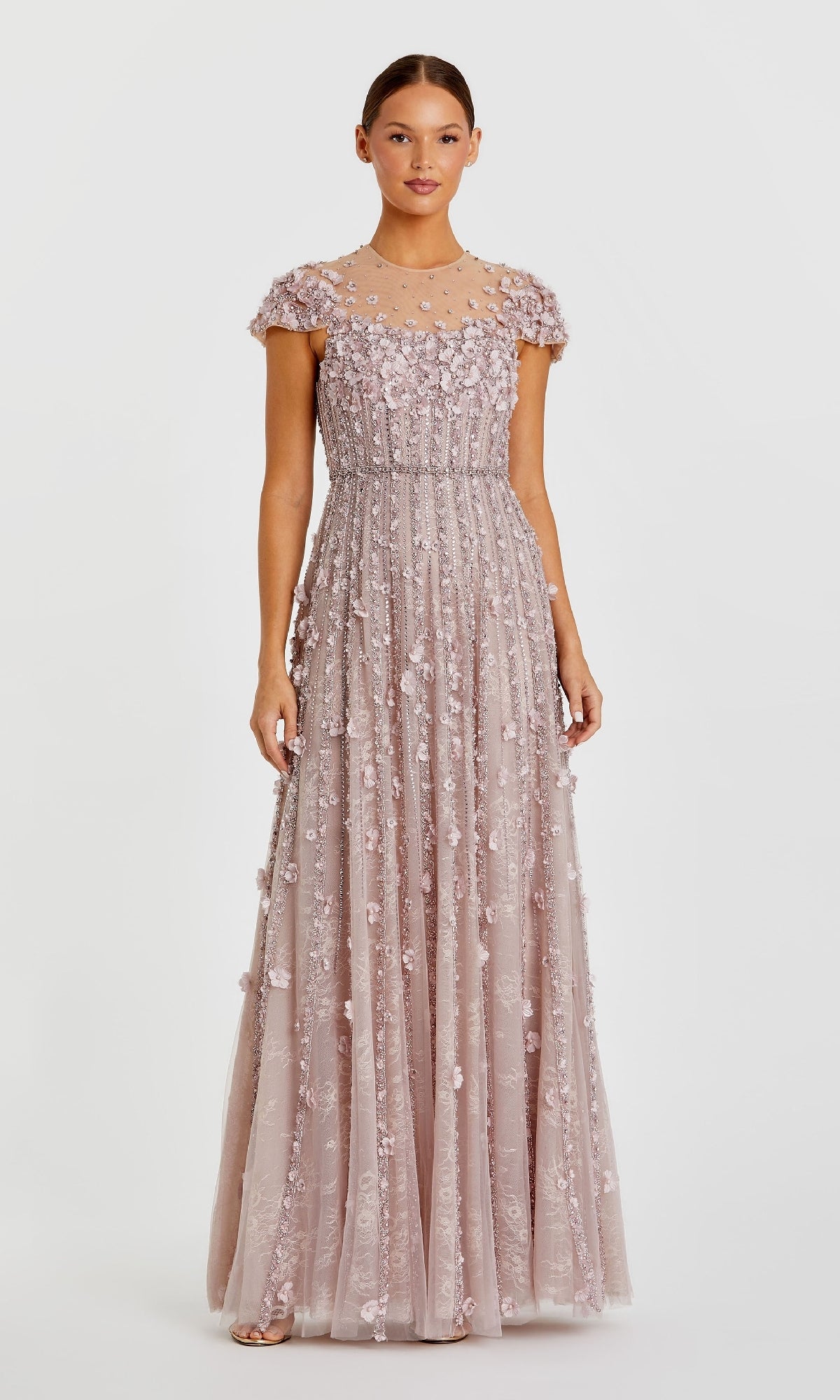 A woman stands wearing the Mac Duggal 11866, a long beaded lilac formal dress.