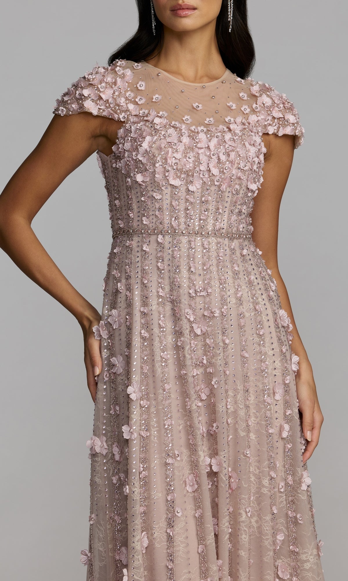 Woman wearing a long, lilac formal dress embellished with beads and 3D floral appliqués, featuring cap sleeves and sheer shoulder detailing—a stunning look inspired by the Mac Duggal 11866 gown.