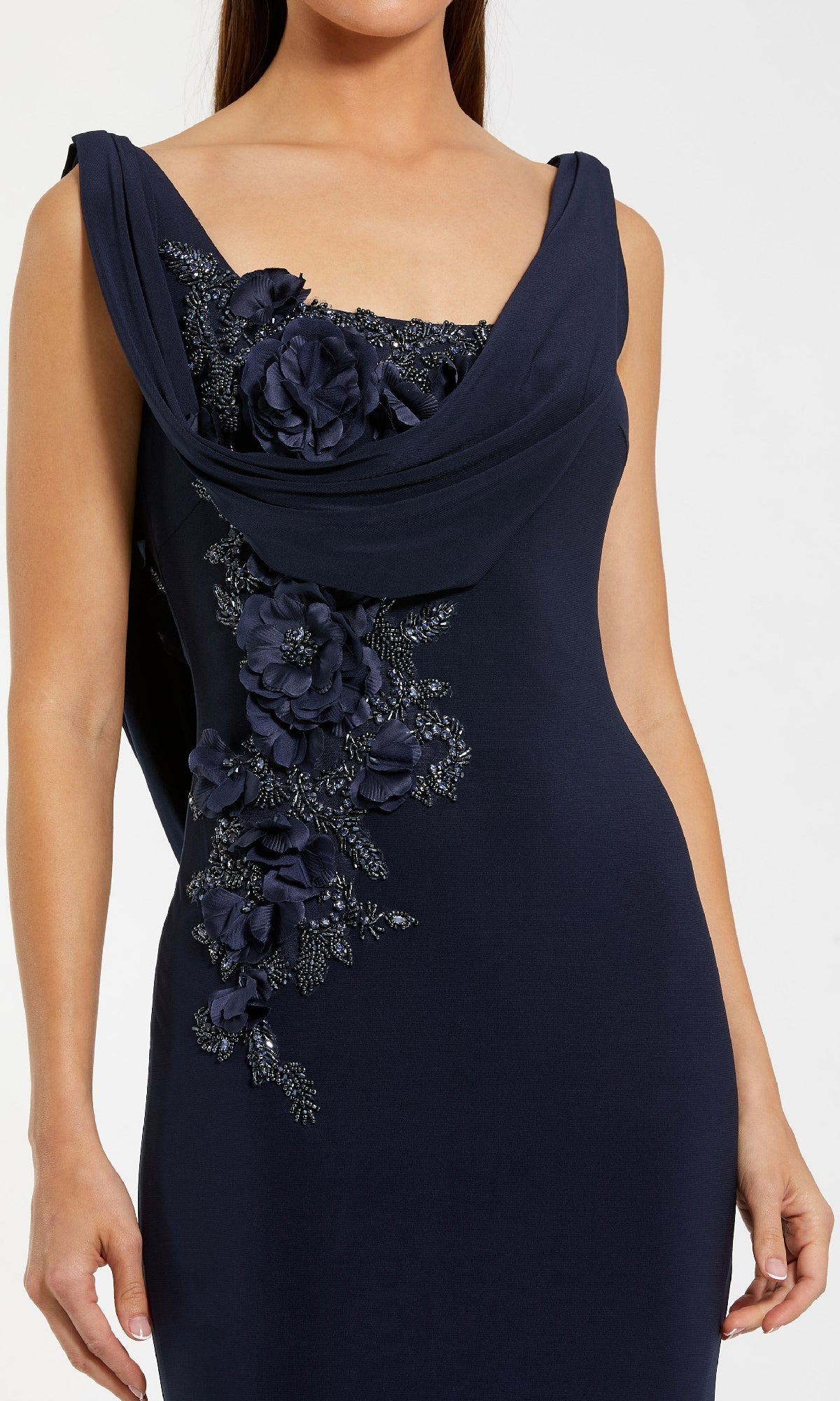 A woman wearing the Mac Duggal 11910 sleeveless navy blue cowl-neck long formal dress, featuring elegant floral appliqué on the bodice, captures timeless evening style.