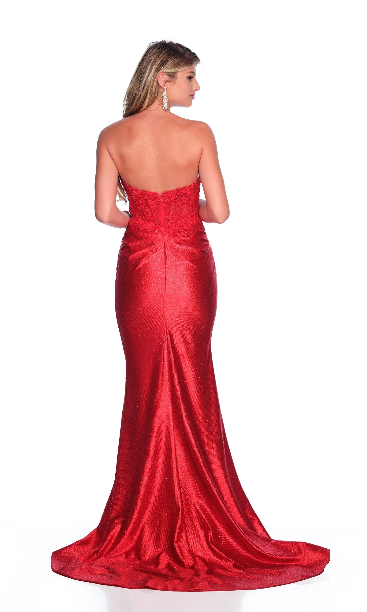 A woman with long, wavy hair and drop earrings faces away, wearing the Dave & Johnny 12206 Red Strapless Prom Dress—a floor-length gown with a fitted bodice, flared train, and sweetheart neckline.