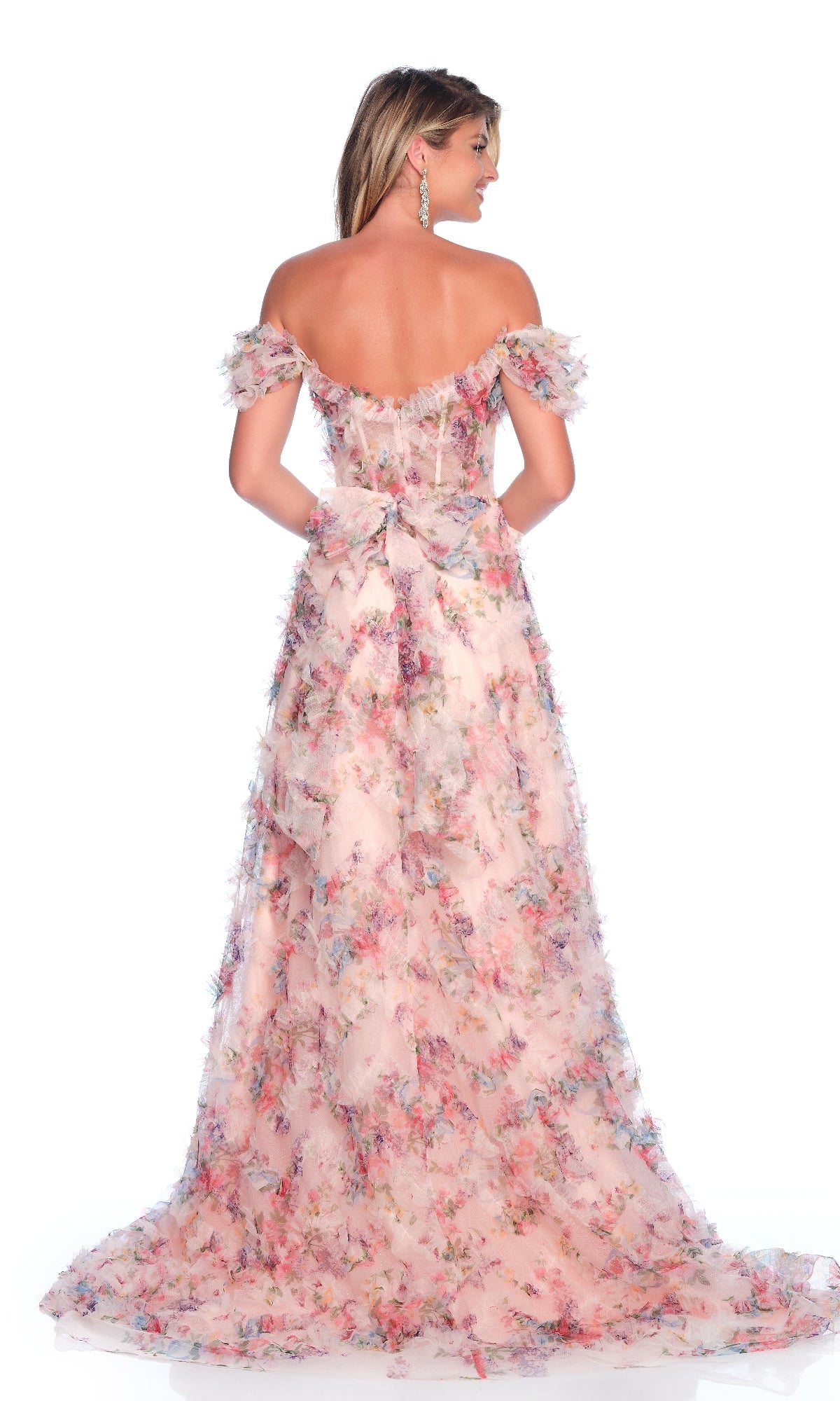 A woman faces away, wearing the Dave & Johnny 12210 Pink Floral Prom Dress with off-the-shoulder sleeves and a back bow, standing against a plain white background.