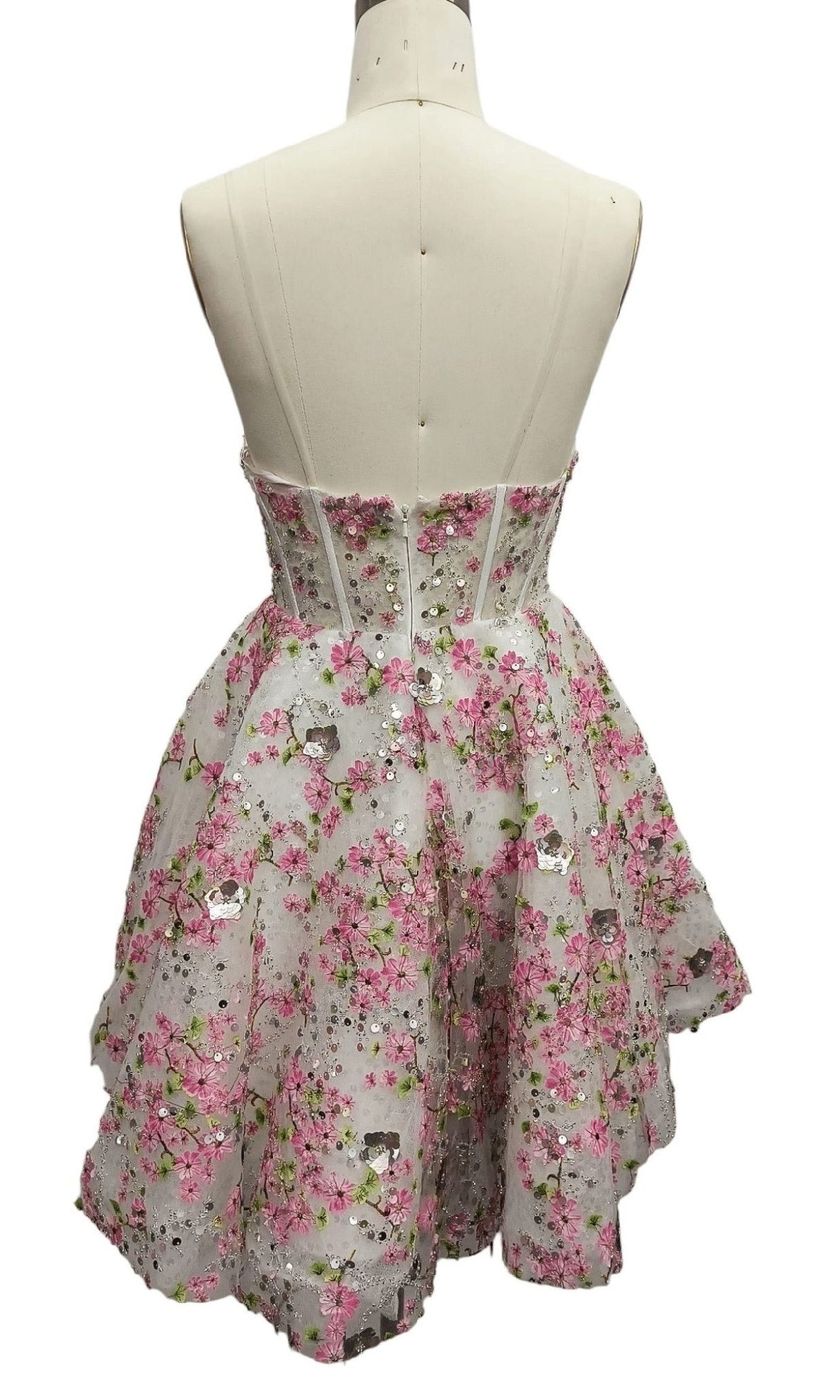 The Strapless Print Hoco Dress: 12375 is a short party dress with a fitted bodice, flared skirt, and pink floral embroidery, shown from the back on a dress form—a perfect dreamy strapless homecoming dress for special occasions.