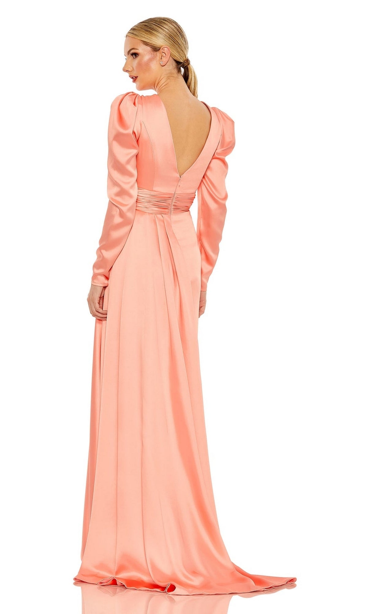 A woman models the Long Formal Dress 12404 by Mac Duggal in peach, featuring long sleeves, a ruched waistband, a deep V-back, and an elegant silhouette as she stands looking over her shoulder.