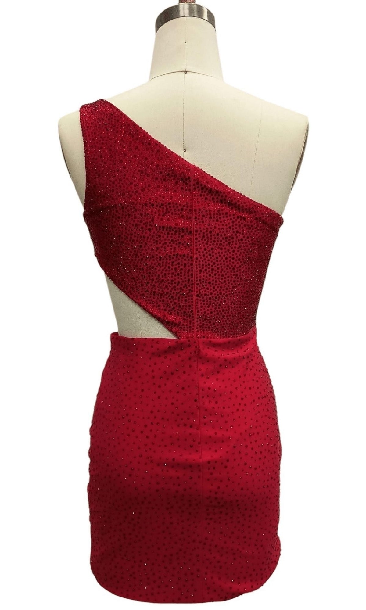 The Cut-Out Short Red Hoco Dress: 12416 is a backless, one-shoulder red mini dress with a diagonal cutout and sparkling embellishments, displayed from the back on a dress form.