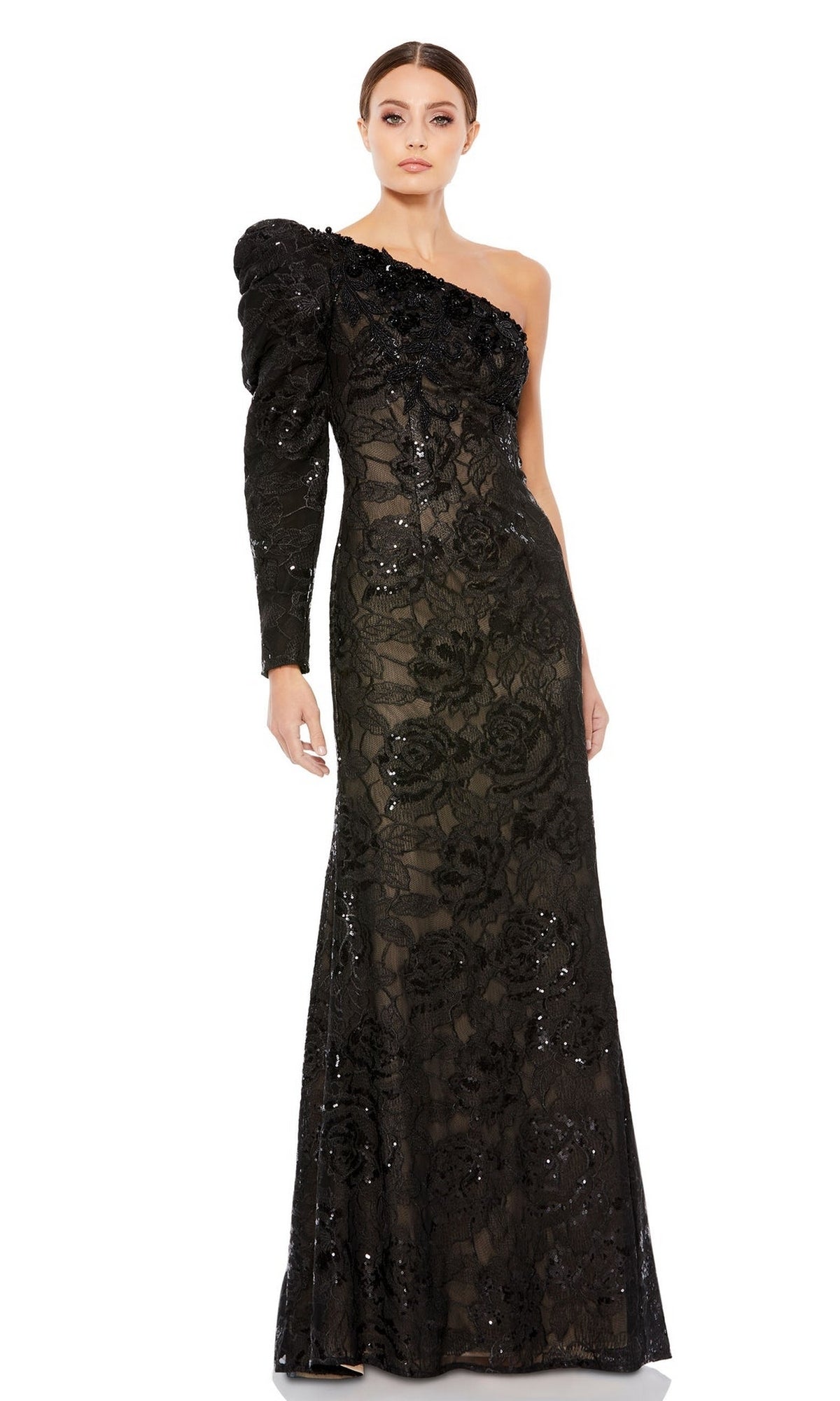 A woman stands against a white background wearing the Long Formal Dress 12444 by Mac Duggal, a black one-shoulder gown featuring floral lace detailing and sparkling sequin embellishments.