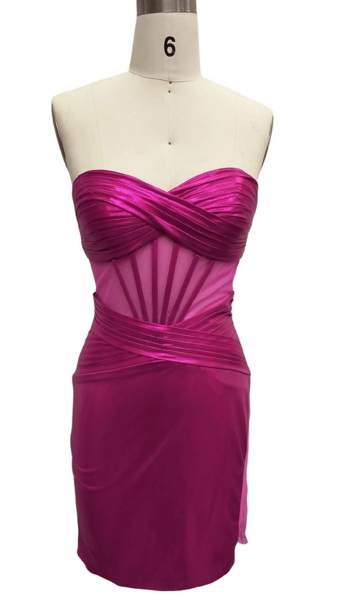The Strapless Fuchsia Pink Hoco Dress: 12565 features a crisscross satin corset bodice, sheer mesh paneling, and a fitted silhouette, displayed on a dress form labeled with the number 6.