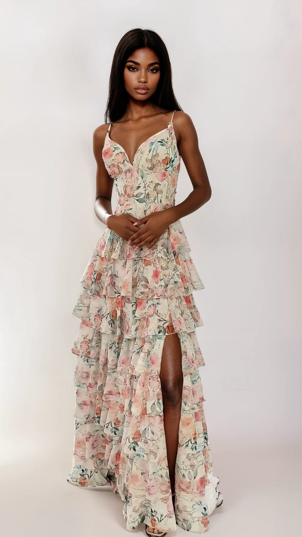 A woman wearing the Dave and Johnny 12948 long prom dress—sleeveless, white floral, with a corset bodice, tiered ruffle skirt, and thigh-high slit—stands against a plain white background.