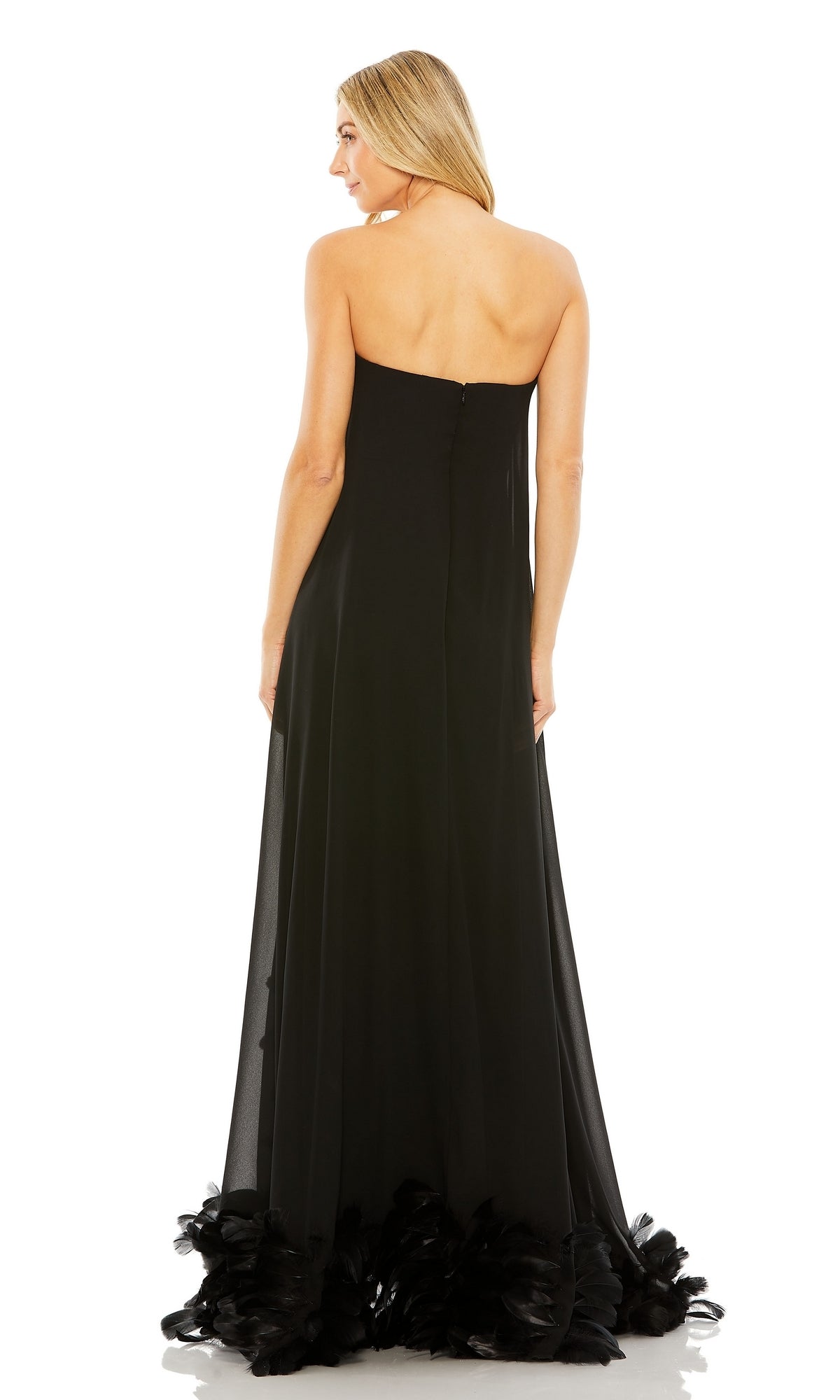 A woman with long blonde hair stands facing away, showcasing the back of a strapless black Strapless Trapeze Formal Gown: Mac Duggal 13001 with a feathered hem.