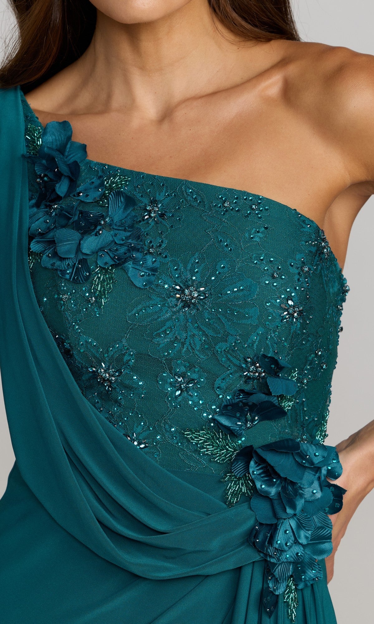 A woman wearing the Mac Duggal 13210 long formal dress in teal, featuring a one-shoulder design with floral lace, intricate beaded embellishments, and delicate 3D flower detailing.