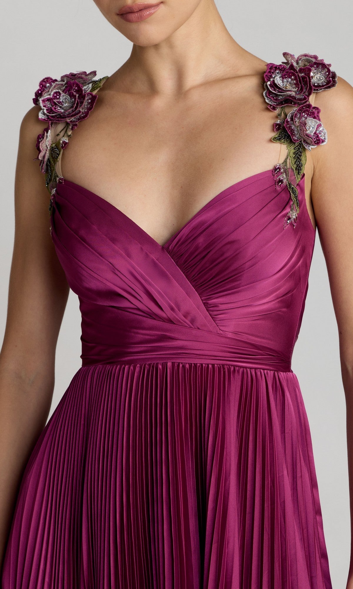 A woman wearing the Mac Duggal 13263 Long Formal Dress in deep magenta, featuring elegant 3D floral straps, a sleeveless satin bodice, and a high-low pleated skirt.