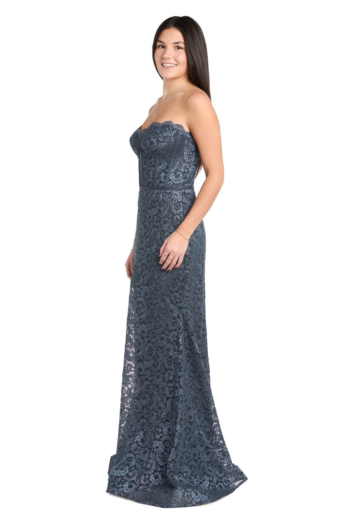 A woman stands slightly to the side against a white background, wearing the Morgan 13269 strapless long lace prom dress in floor-length dark blue.