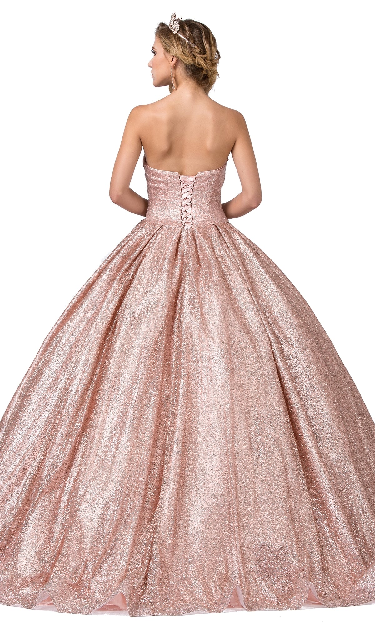 A woman stands facing away from the camera wearing the Quinceanera Dress 1341 by Dancing Queen—a strapless, sweetheart neckline ball gown in sparkling pink with a lace-up back.
