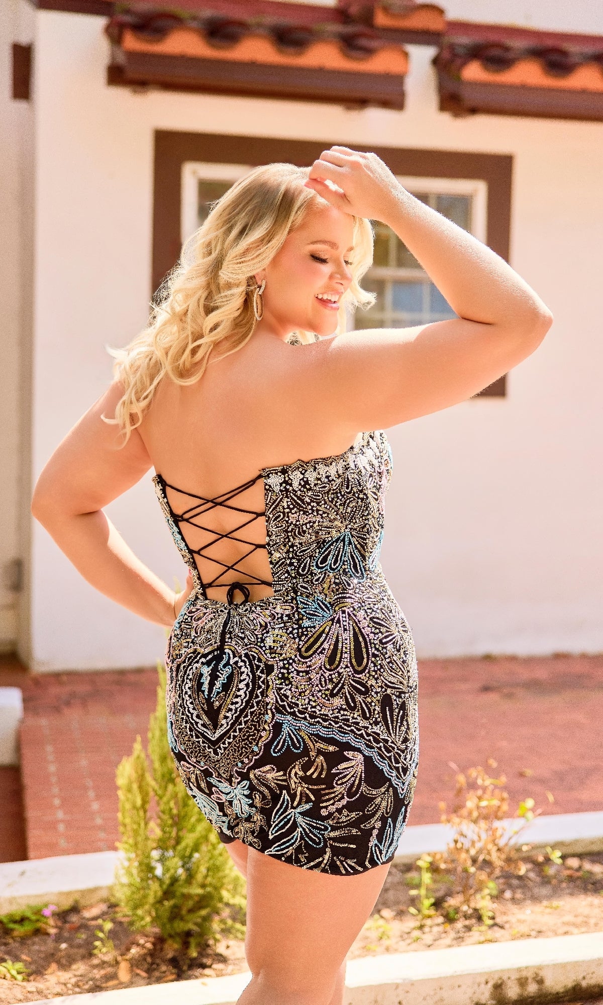 Woman wearing a patterned dress with a back detail, standing outdoors.