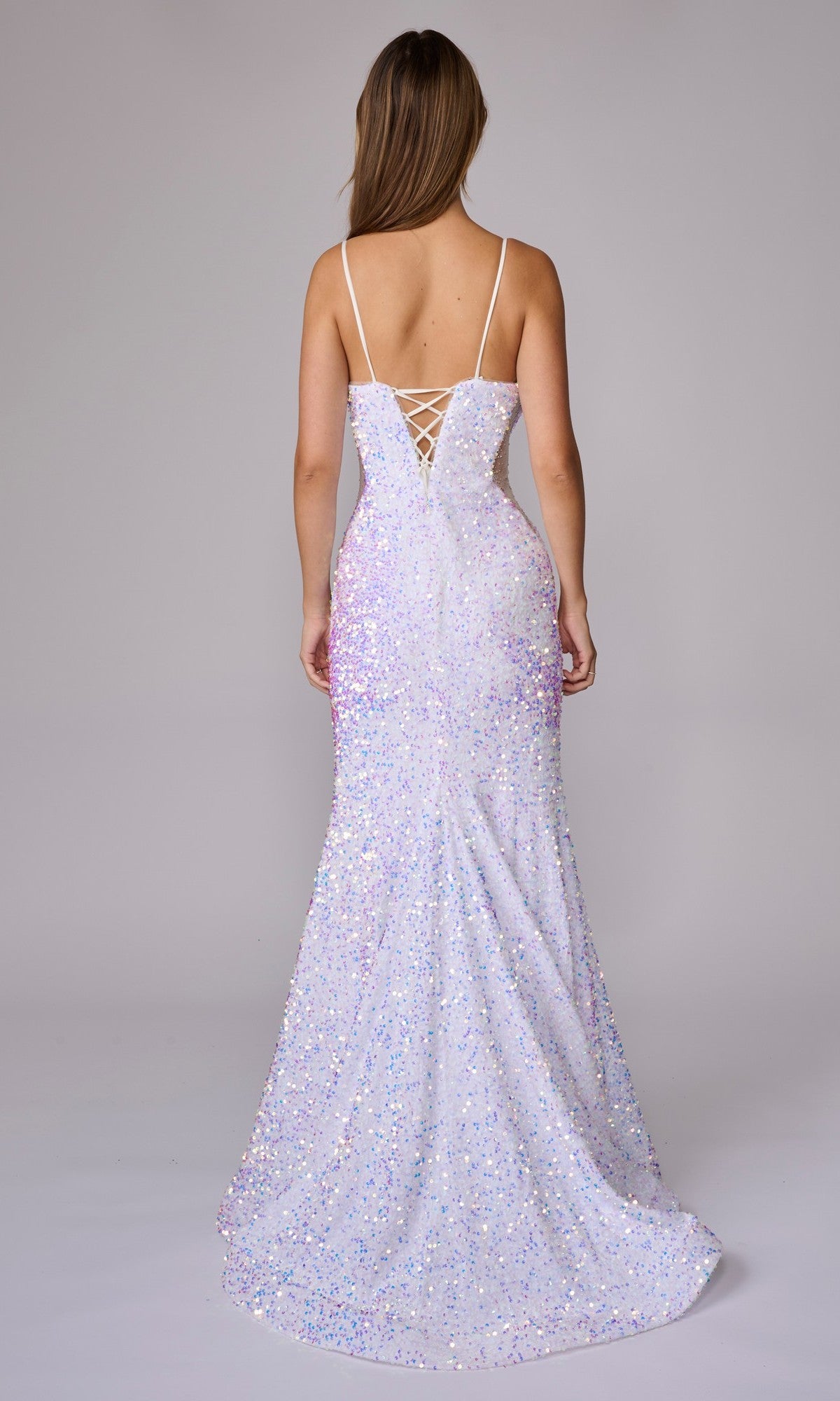 Woman wearing the Nina Canacci 1616 long formal dress, a backless, floor-length white sequin gown with thin straps and adjustable lace-up back, shown from behind against a plain background.