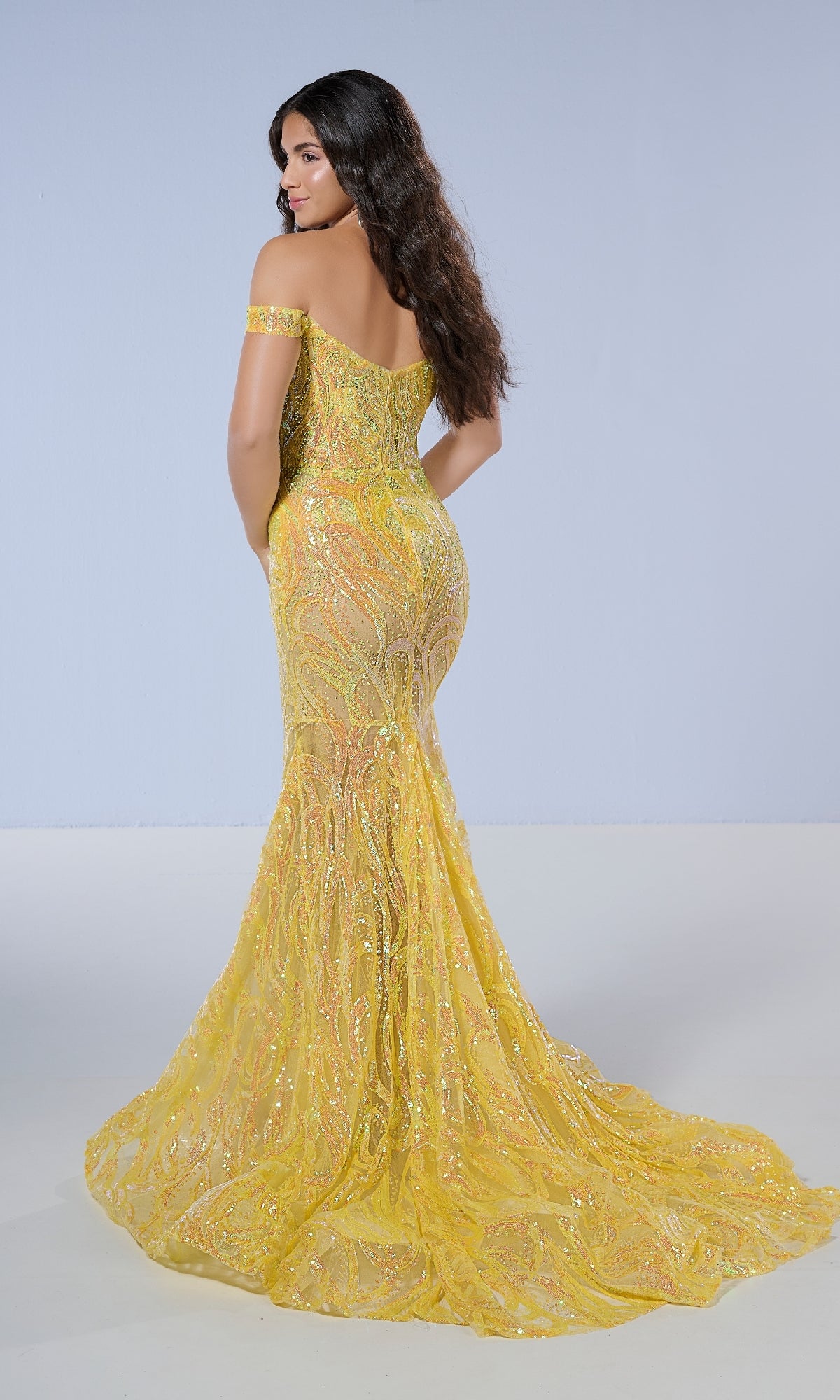 A woman models the Tiffany 16224 long prom dress, featuring an off-the-shoulder fitted mermaid silhouette with yellow sequins, standing with her back to the camera against a plain background.