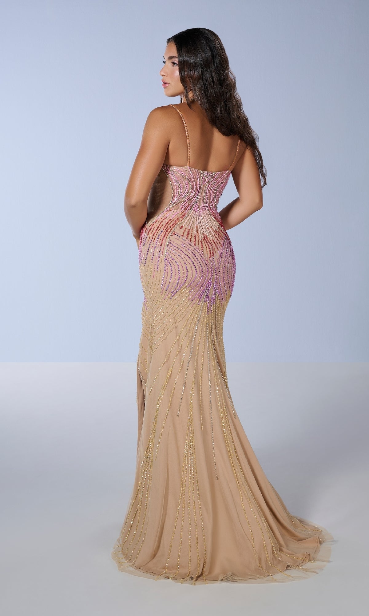 A woman with long dark hair models the Tiffany 16225 prom dress, a fitted nude sequin gown with pink and gold bead accents and a subtle thigh-high slit, posing against a light background with her back to the camera.