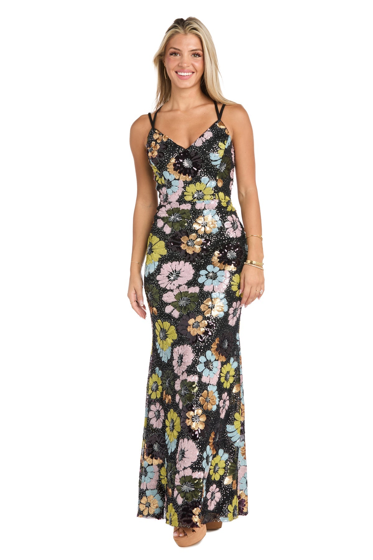 A woman stands facing forward, smiling in the sleeveless Floral-Sequin Long Black Prom Dress: Morgan 19051, featuring multicolored floral patterns for an elegant prom look.