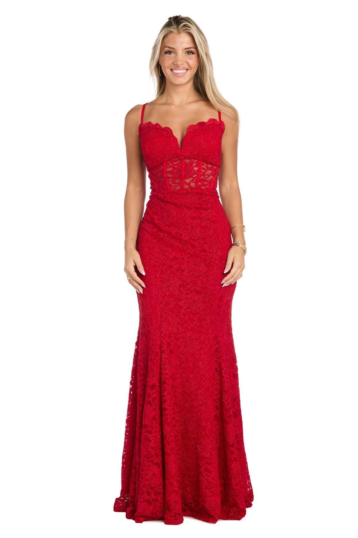 A woman stands against a plain white background wearing the Long Red Lace Prom Dress: Morgan 19069, a sleeveless, floor-length gown featuring a fitted bodice and sheer corset detailing.