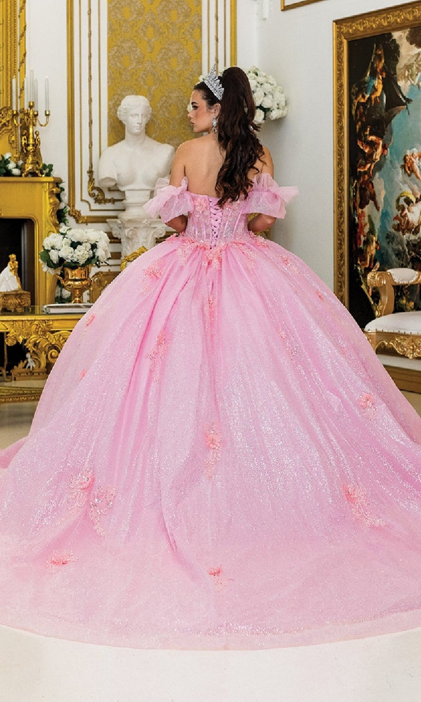 A woman in the Quinceanera Dress 1990 by Dancing Queen, featuring a glitter corset bodice, stands facing away in an ornate room with gold accents, a white statue, and classical paintings.