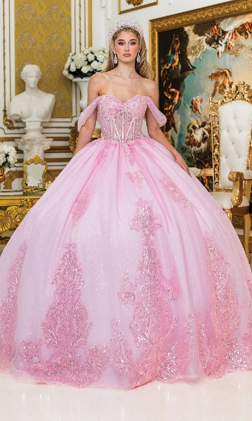 In an ornate room with gold accents and classical artwork, a woman wears the Quinceanera Dress 1997 By Dancing Queen—a sparkling pink gown with off-the-shoulder sleeves, intricate lace, and sequin appliques.