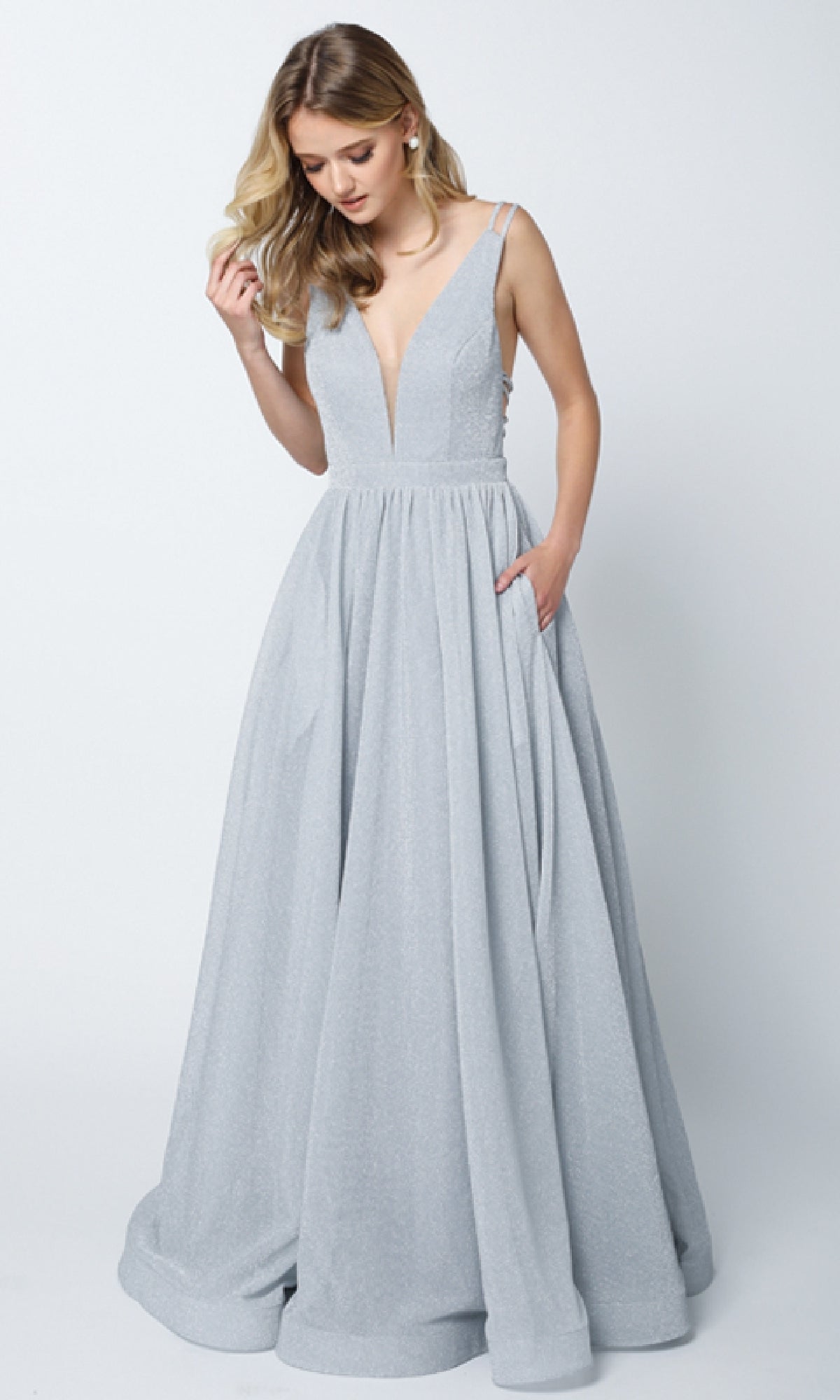 Woman in the Juliet 201 long prom dress—sleeveless, floor-length, silver glitter with an A-line skirt, deep V-neckline, and pockets—stands against a plain light background.