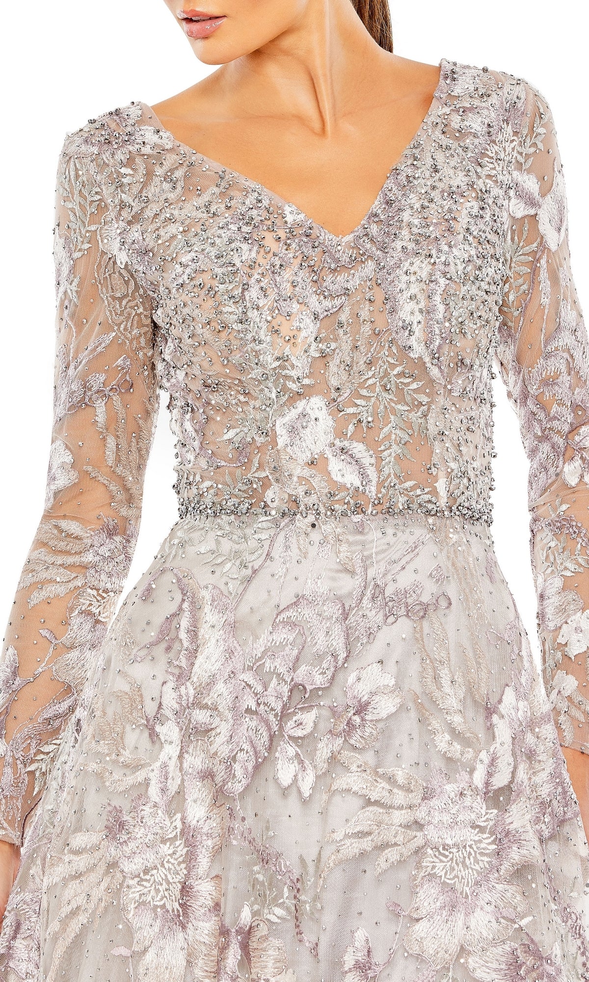 A woman wears the Mac Duggal 20214 long sleeve formal dress, featuring silver and lavender hues with intricate beadwork and floral embroidery.