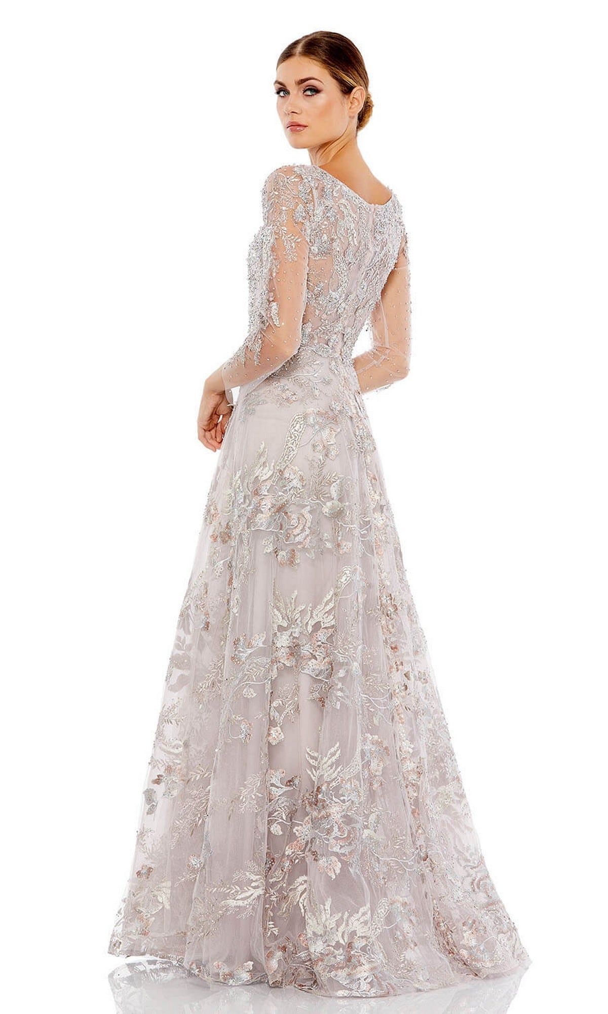 A woman wearing the Mac Duggal 20245 Long Violet Lace Formal Dress, featuring sheer long sleeves and intricate floral embroidery, stands with her back slightly turned.