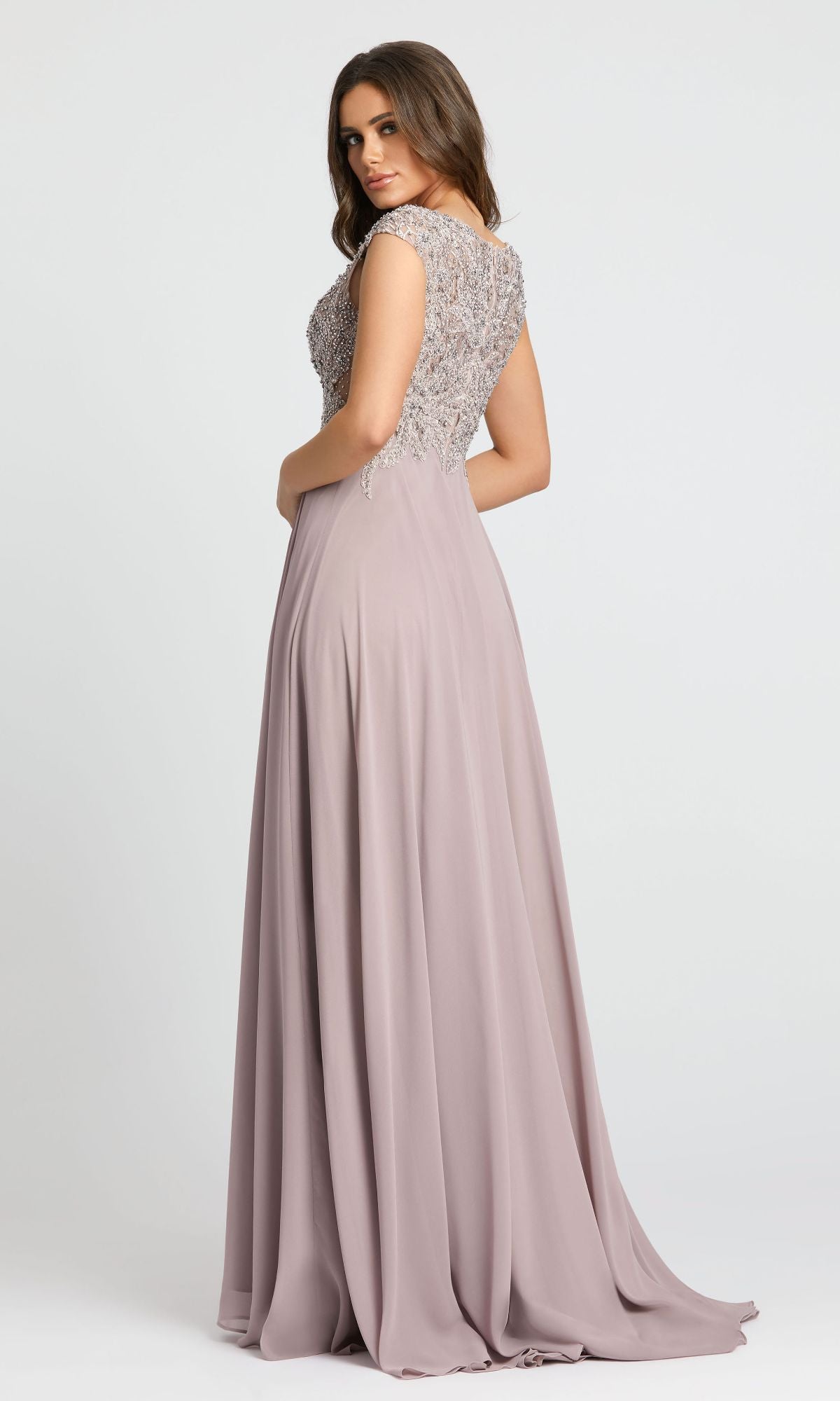 A woman faces away from the camera in the Mac Duggal 20264 Beaded-Bodice Long Formal Dress, featuring a mauve A-line silhouette and a beaded V-neck bodice.