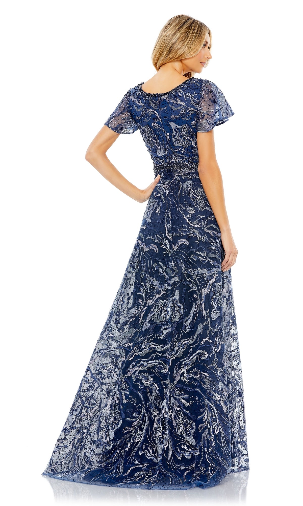A woman poses from the back in the Mac Duggal 20301 short-sleeve formal dress, featuring a floor-length design with silver embroidery and a beaded waist.