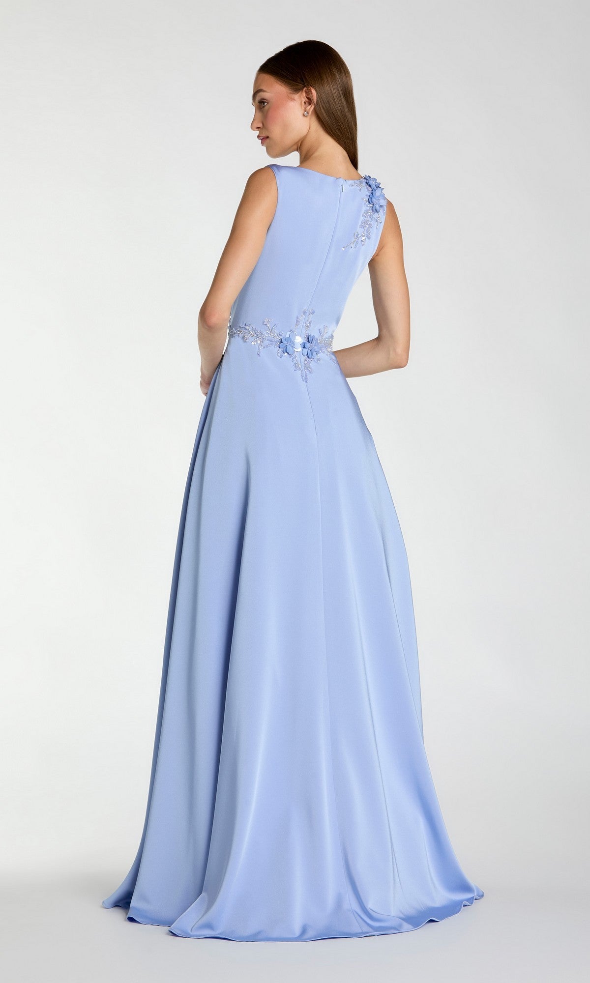 A woman faces away from the camera, wearing the Mac Duggal 20365 sleeveless long formal dress in light blue, which features floral embellishments on the shoulder and waist.