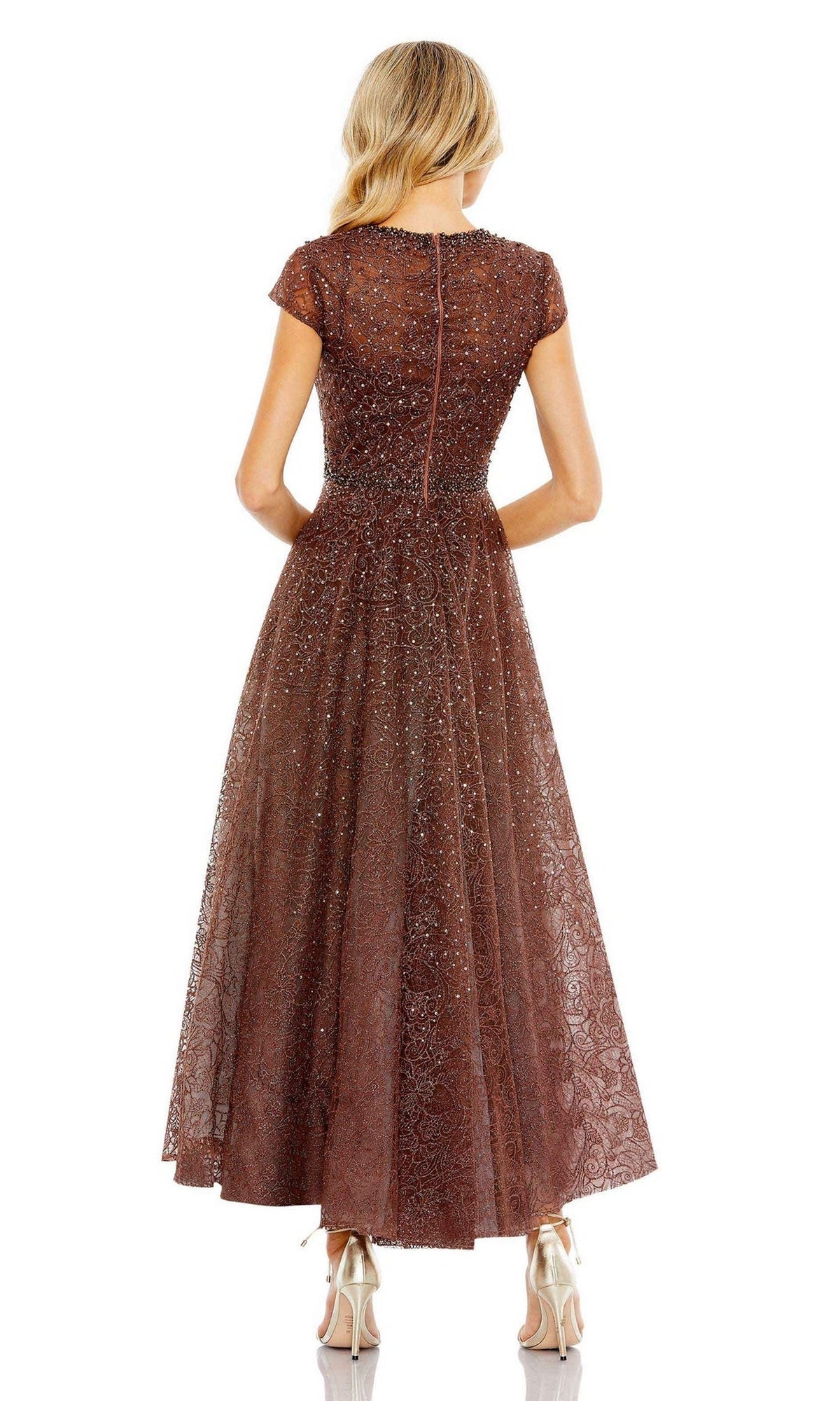 A woman faces away, wearing the Mac Duggal 20371 Cap Sleeve A-Line Formal Dress in brown with a subtle shimmer and lace texture, stylishly paired with metallic high-heeled shoes.
