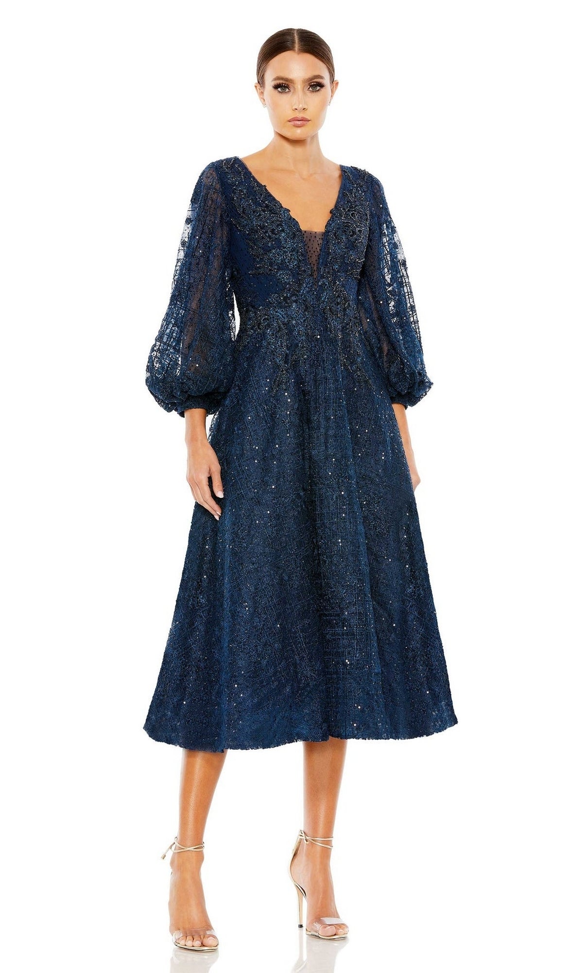 A woman wears the Mc Duggal 20391 Blue Midi Wedding Guest Dress with long lace balloon sleeves and silver heels, styled chicly as a semi-formal outfit against a plain white background.