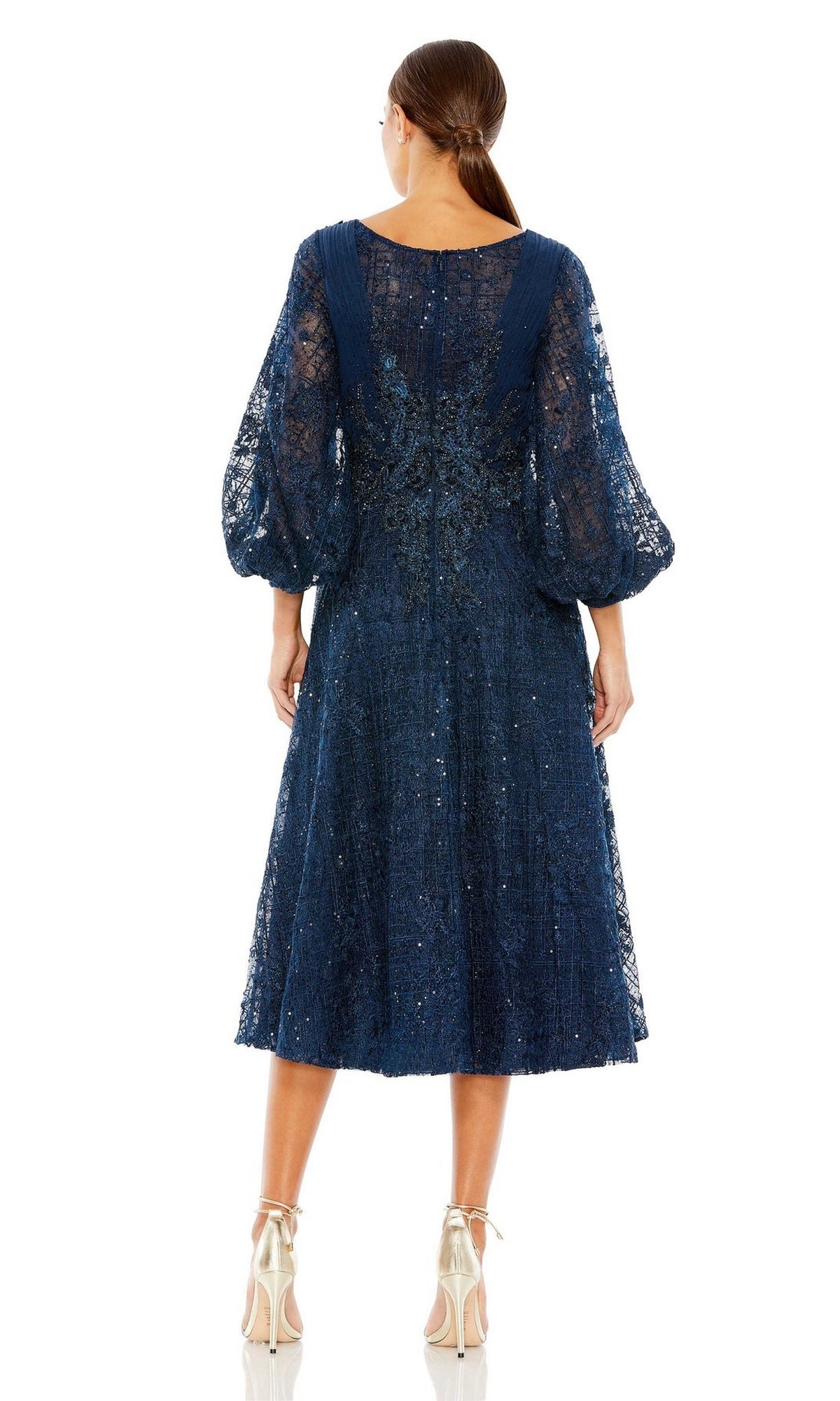 A woman faces away wearing the Mc Duggal 20391 Blue Midi Wedding Guest Dress with sheer long sleeves and silver heels—a chic semi-formal dress ideal for any occasion.