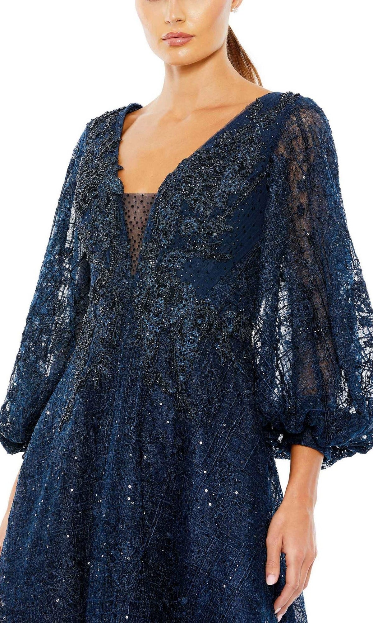 A woman in the Mc Duggal 20391 Blue Midi Wedding Guest Dress featuring navy lace, three-quarter sheer sleeves, bead detailing, and a deep V neckline—an elegant semi-formal choice for special occasions.