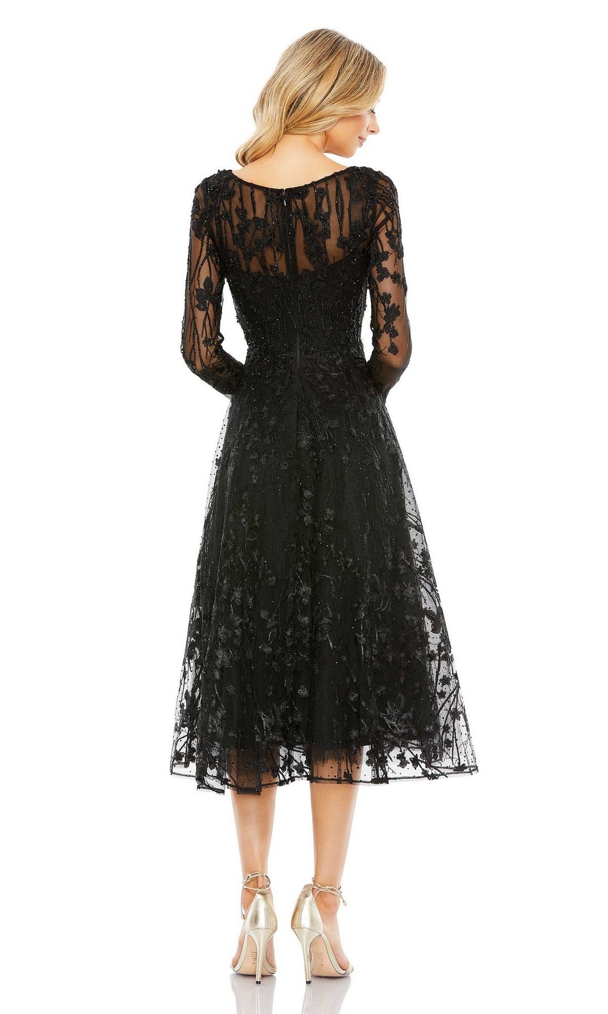 A woman faces away, wearing the Mac Duggal Sleeved Black Wedding-Guest Dress 204041 with sheer long sleeves and embellished embroidery, paired with beige high heels against a white background.